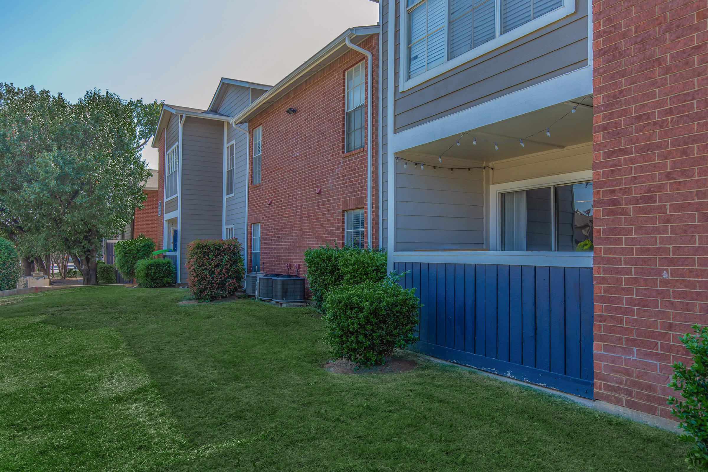 a large brick building with grass in front of a house