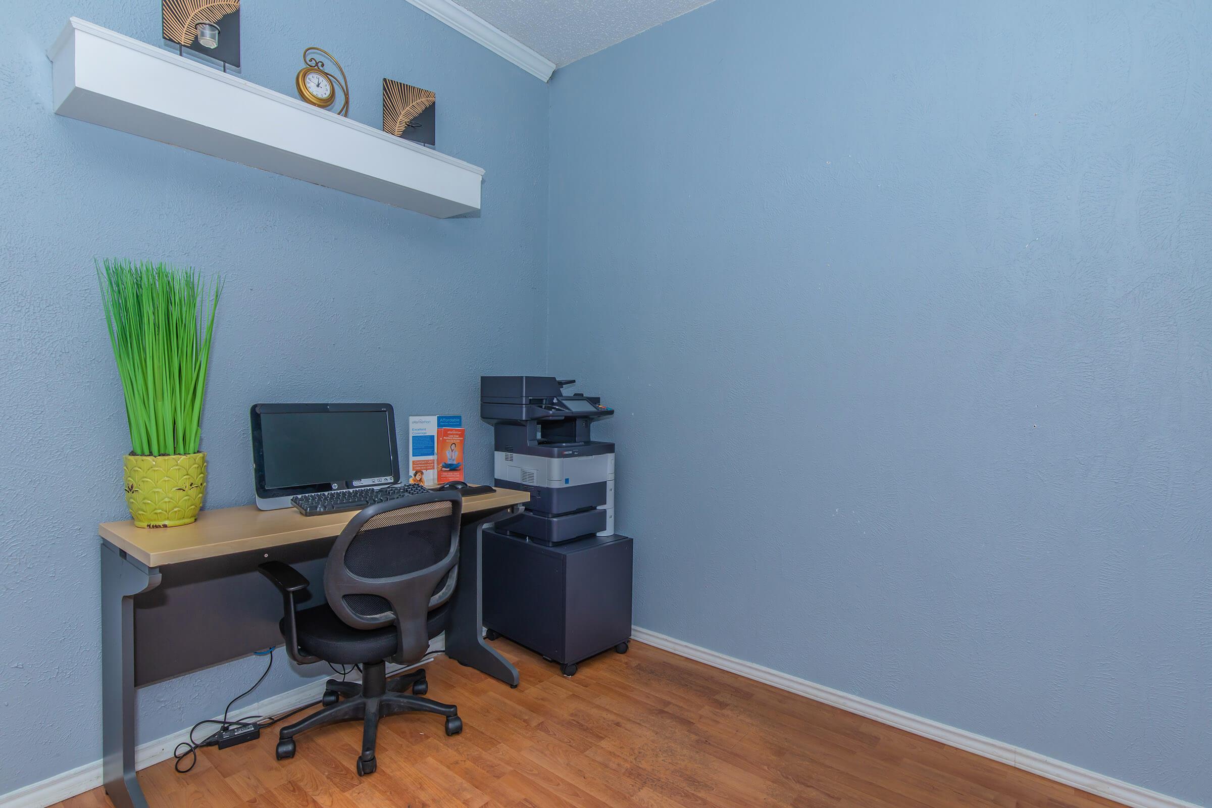 a desk with a computer and a chair in a room