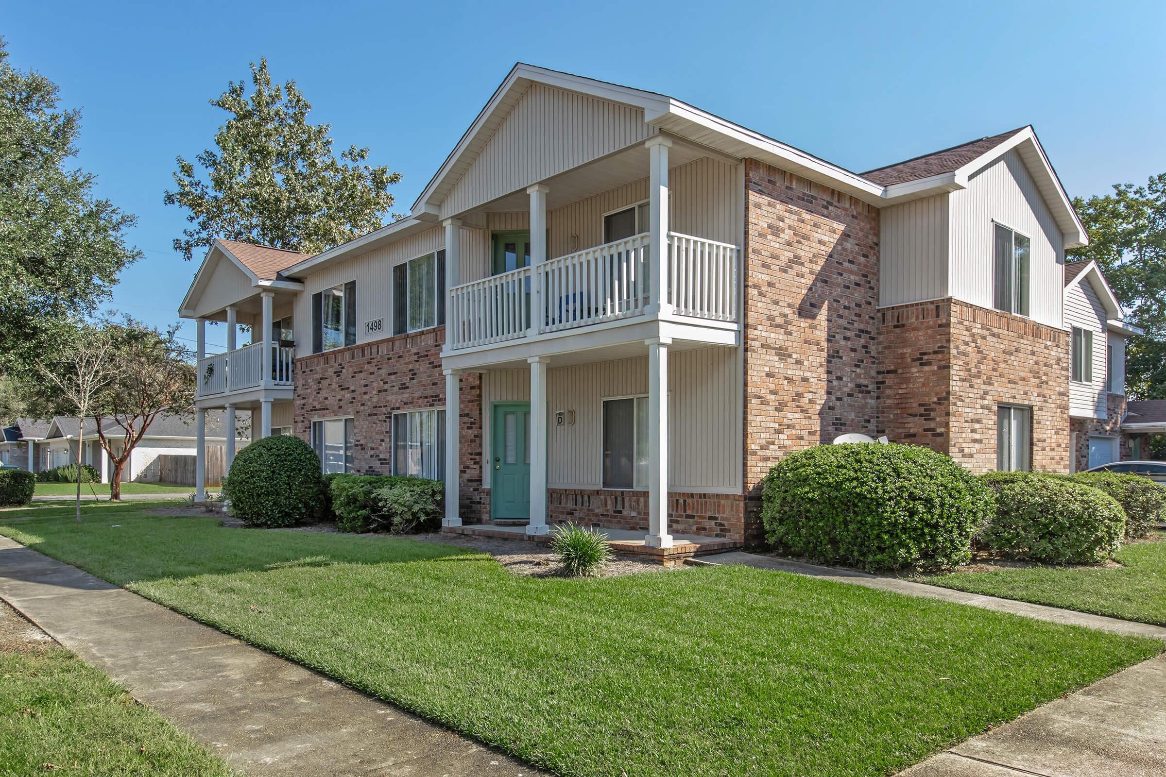 a large brick building with grass in front of a house