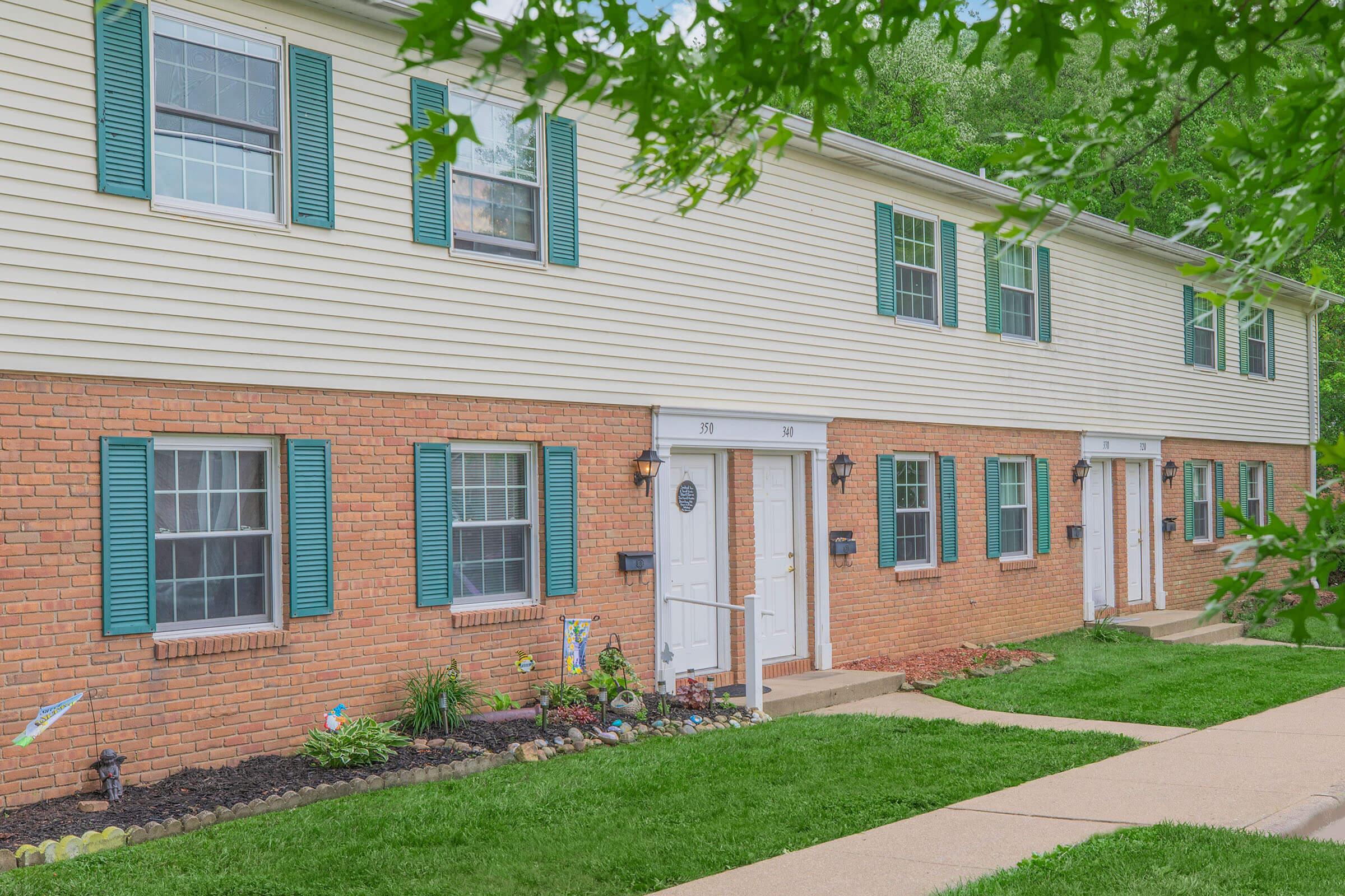 a large brick building with grass in front of a house