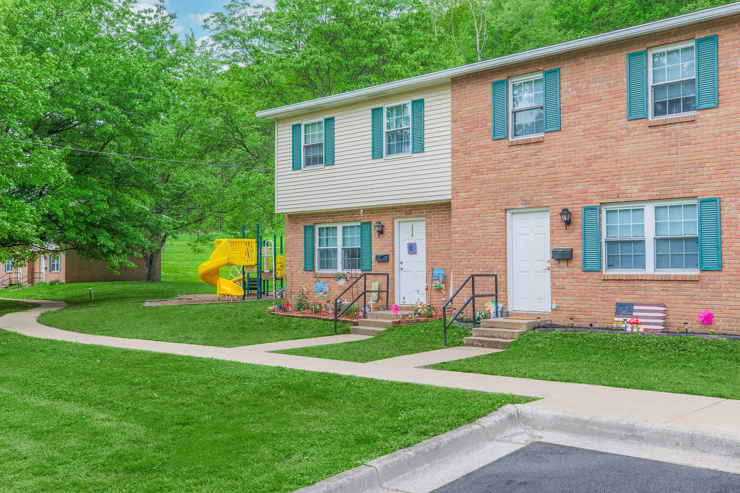 a large brick building with grass in front of a house