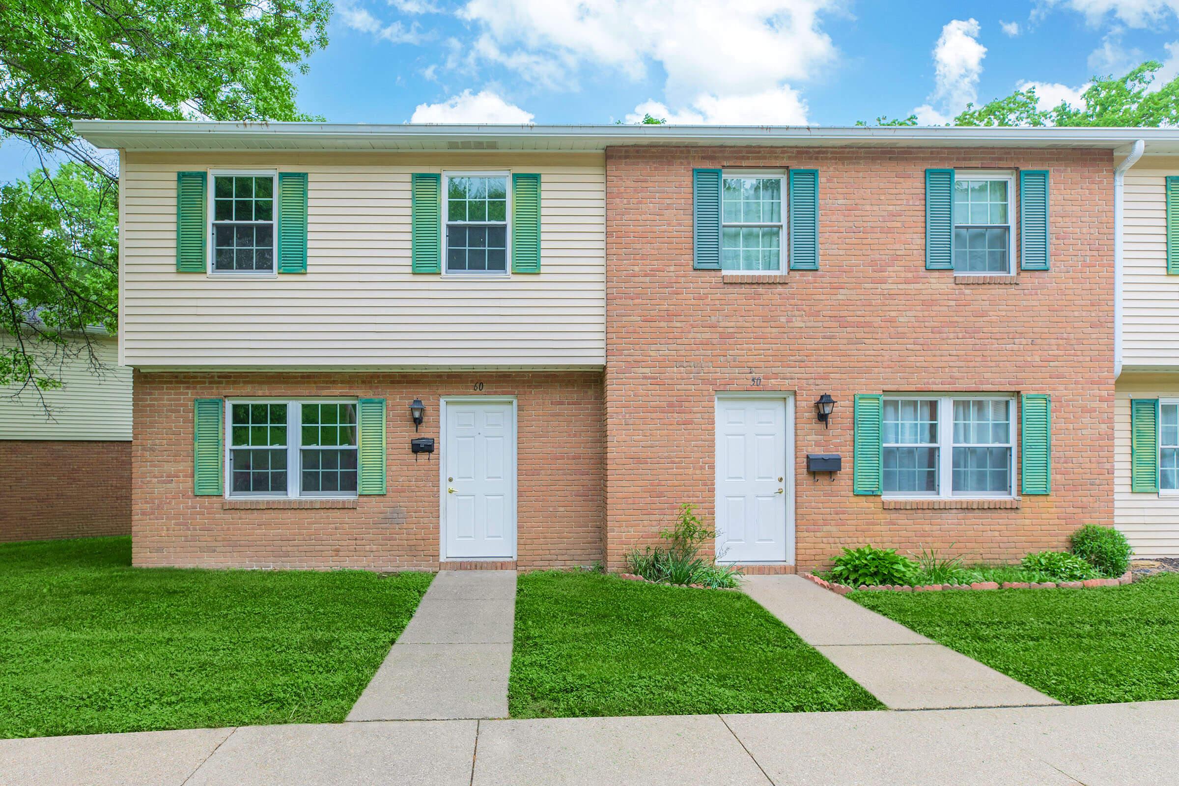 a large brick building with grass in front of a house