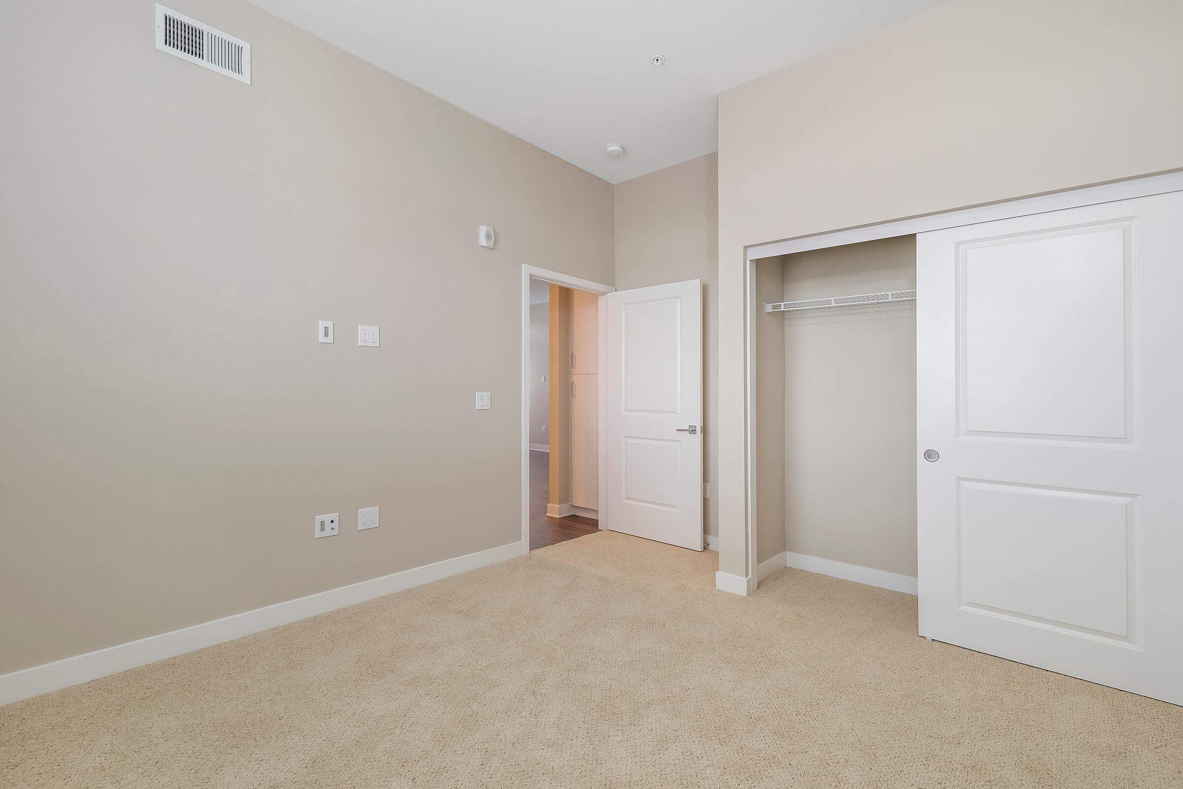 Carpeted bedroom with open sliding closet doors