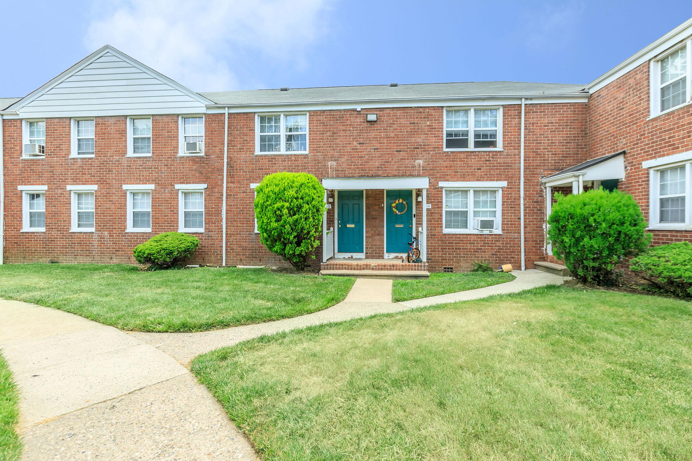 a large brick building with grass in front of a house