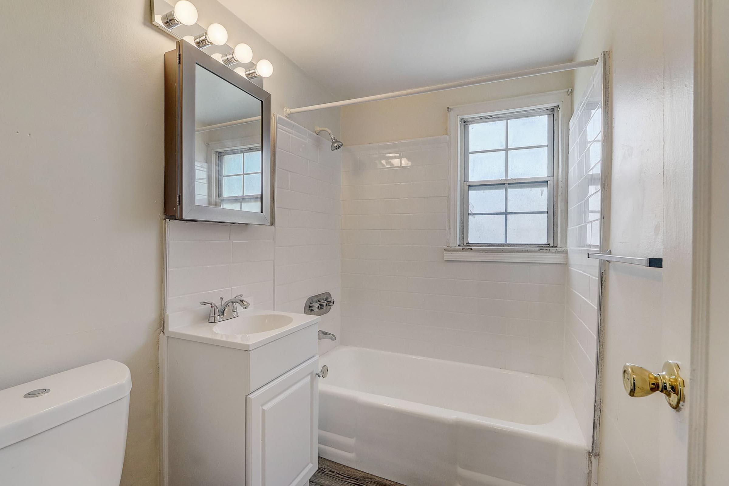 a sink sitting under a window next to a shower