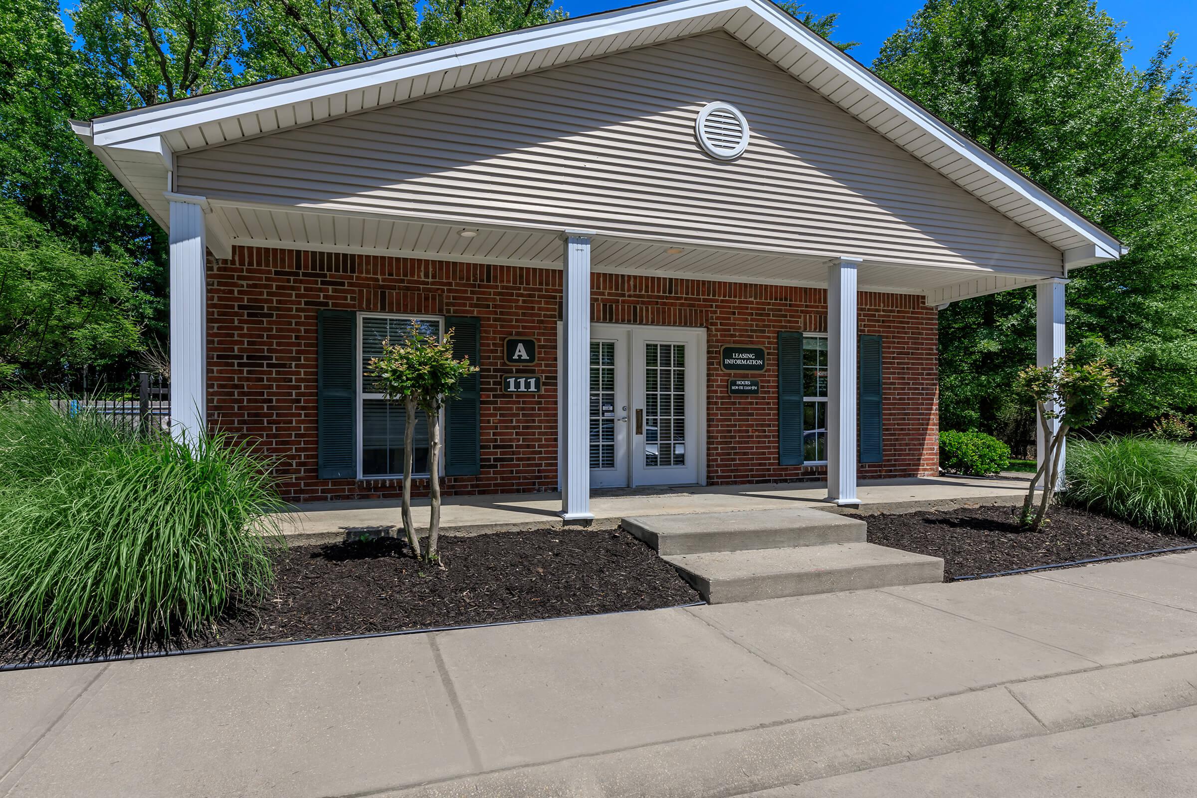 a house with bushes in front of a brick building