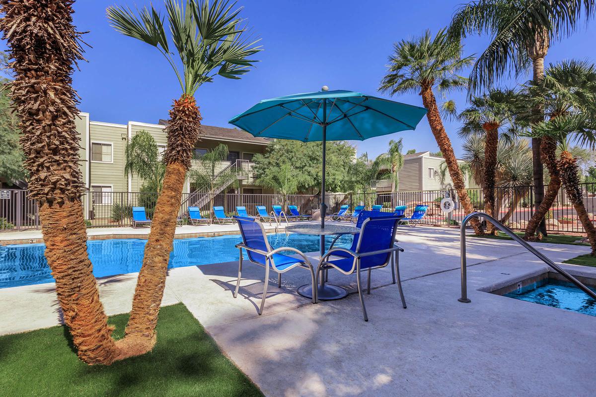 a table topped with a blue umbrella next to a palm tree