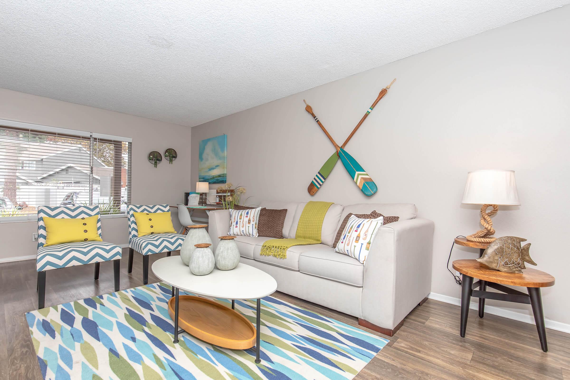 1 Bedroom Apartments in Oceanside CA - The Dylan - Living Room with High Textured Ceilings, Ceiling Fan, Wood-Style Flooring, and Expansive Windows.