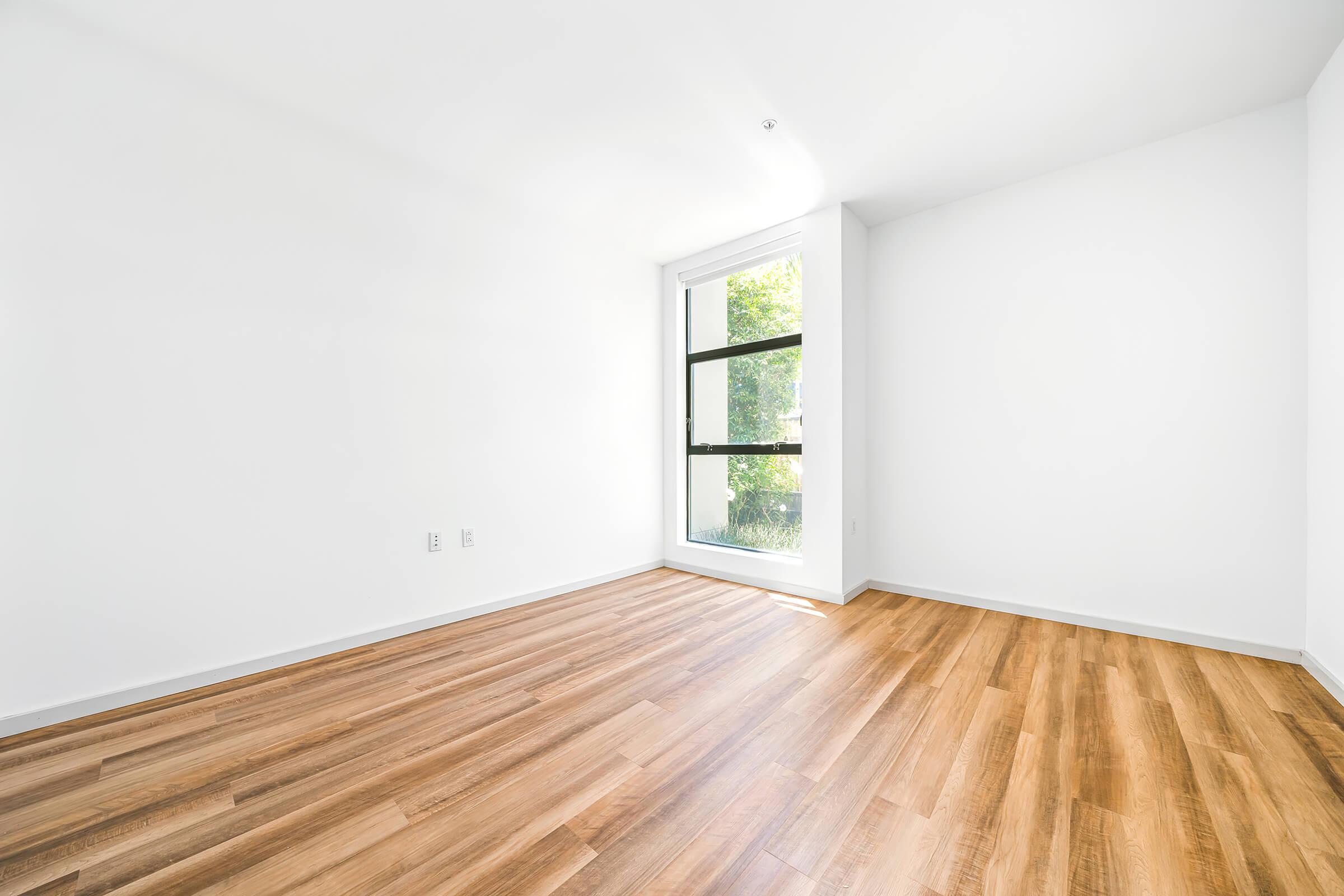 vacant bedroom with wooden floors and a window