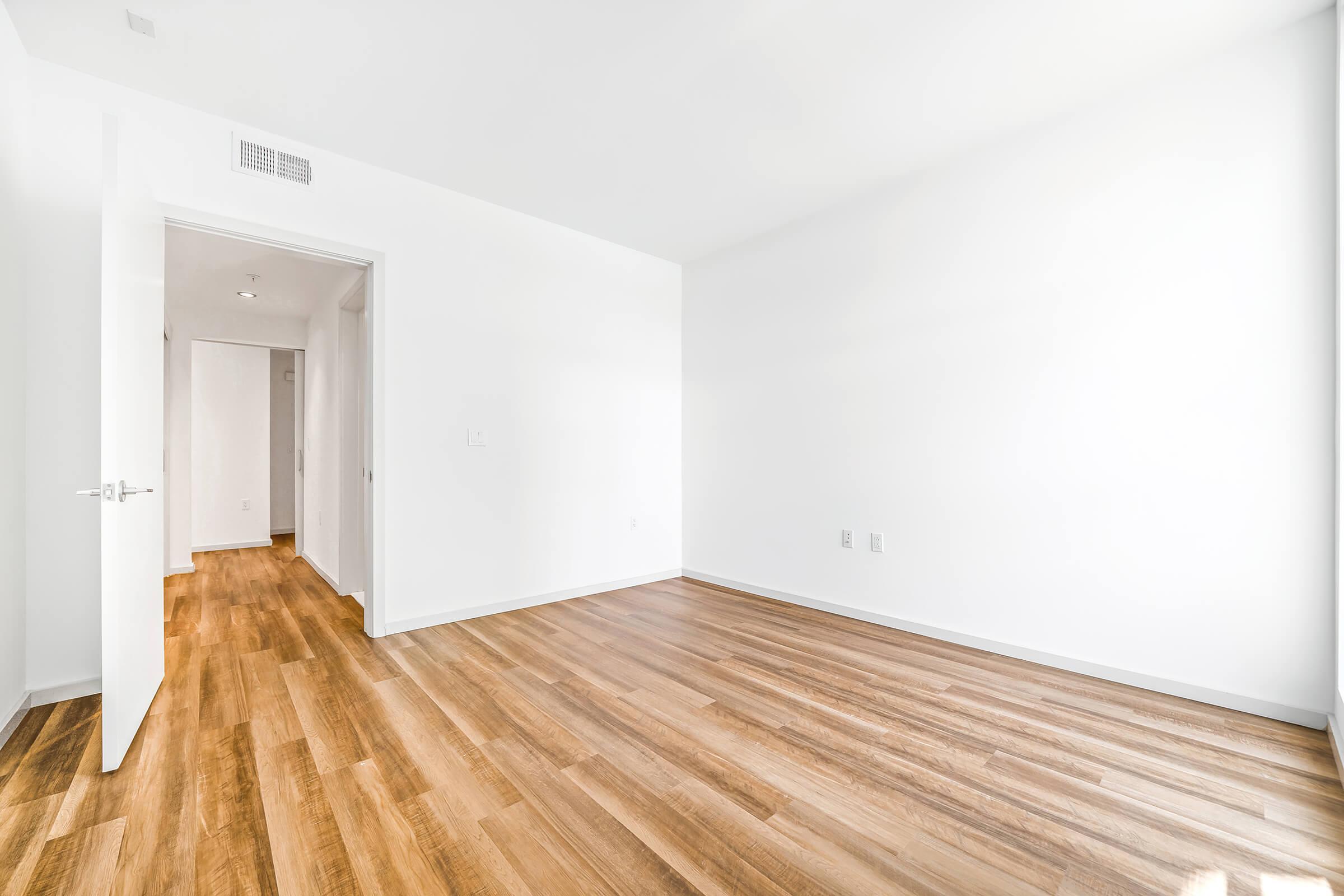 vacant bedroom and hallway with wooden floors