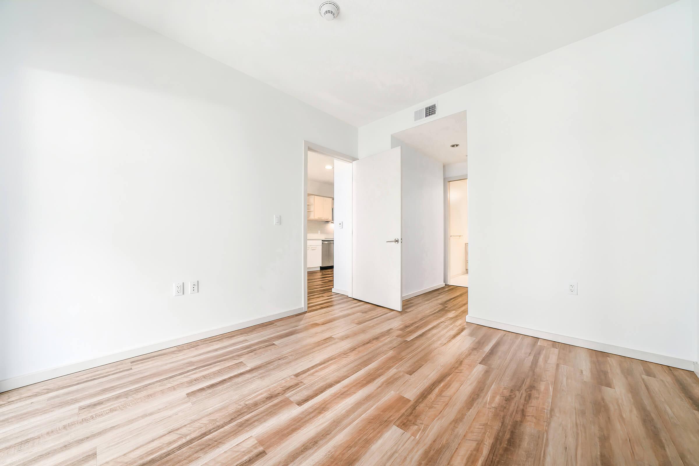 unfurnished bedroom and hallway with wooden floors
