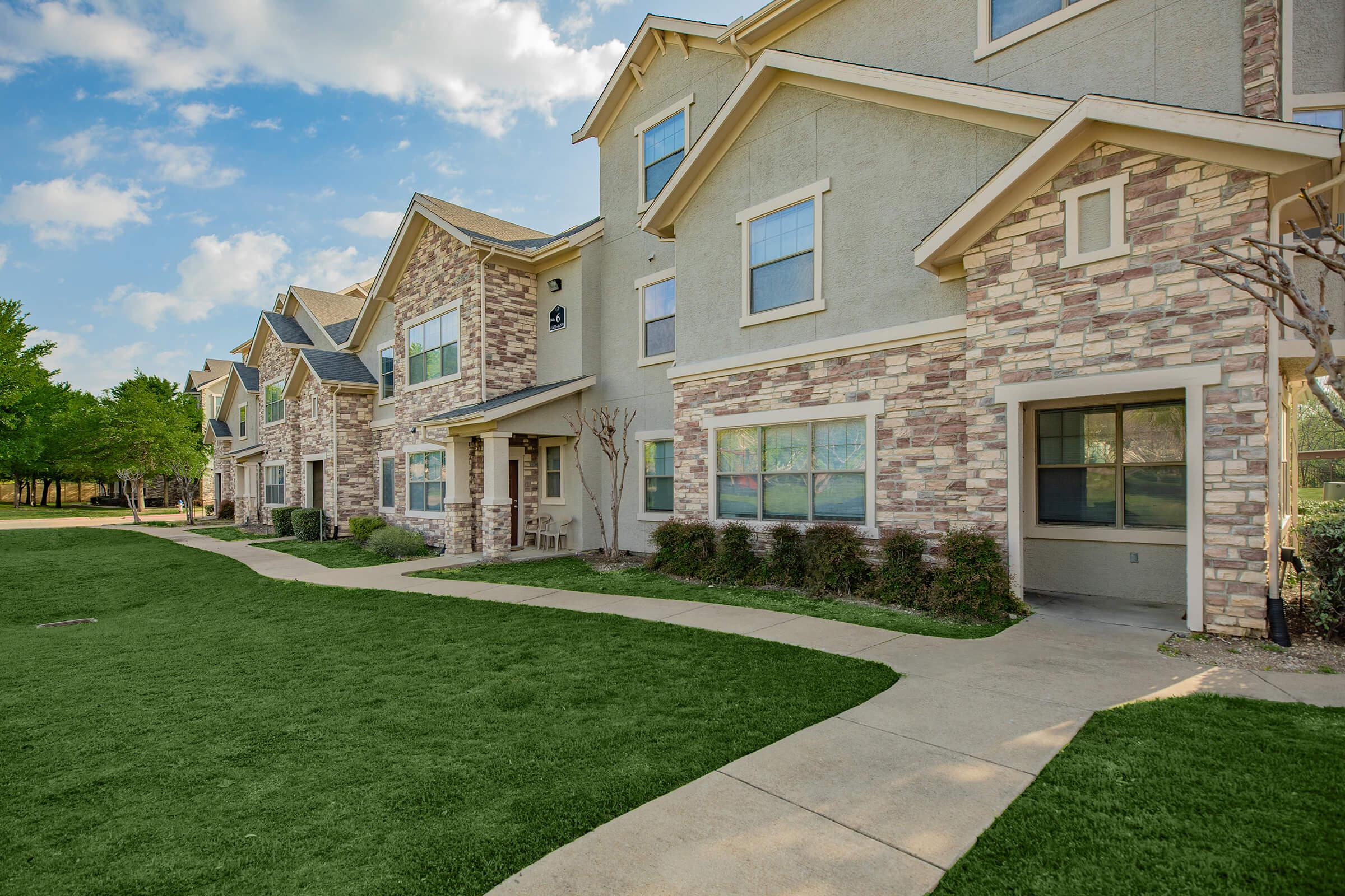 a large brick building with grass in front of a house