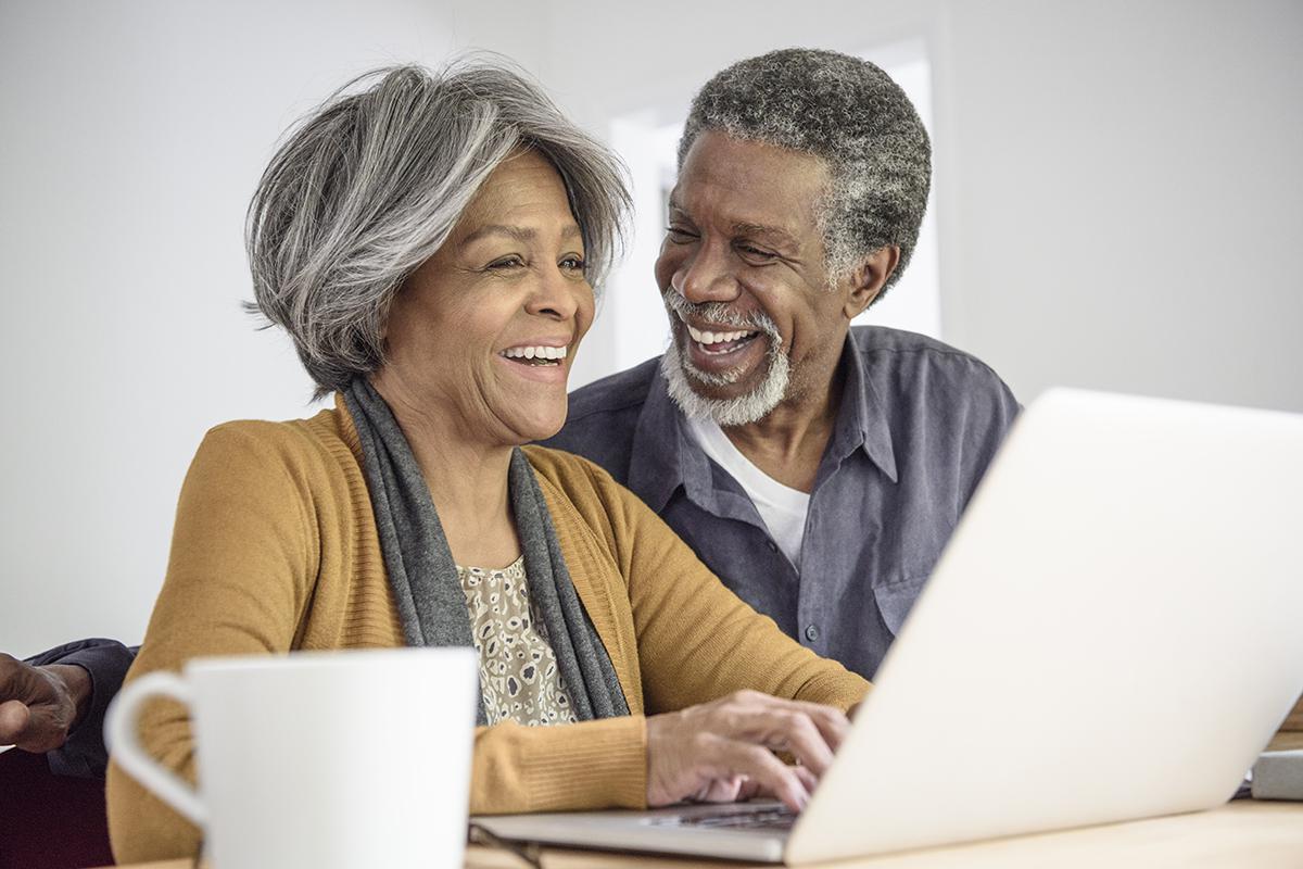 a man and a woman sitting at a table using a laptop