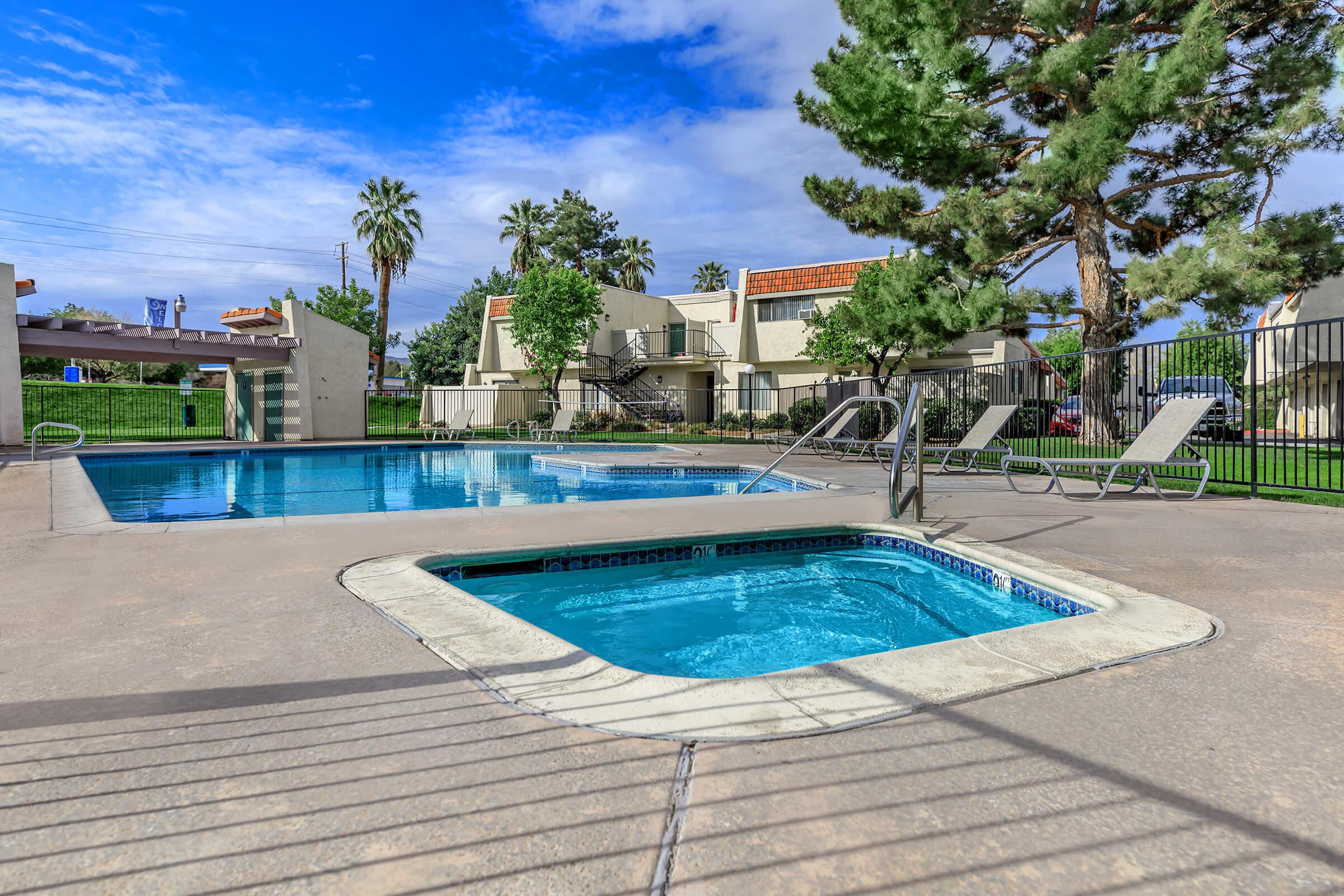 the community pool and spa with green trees