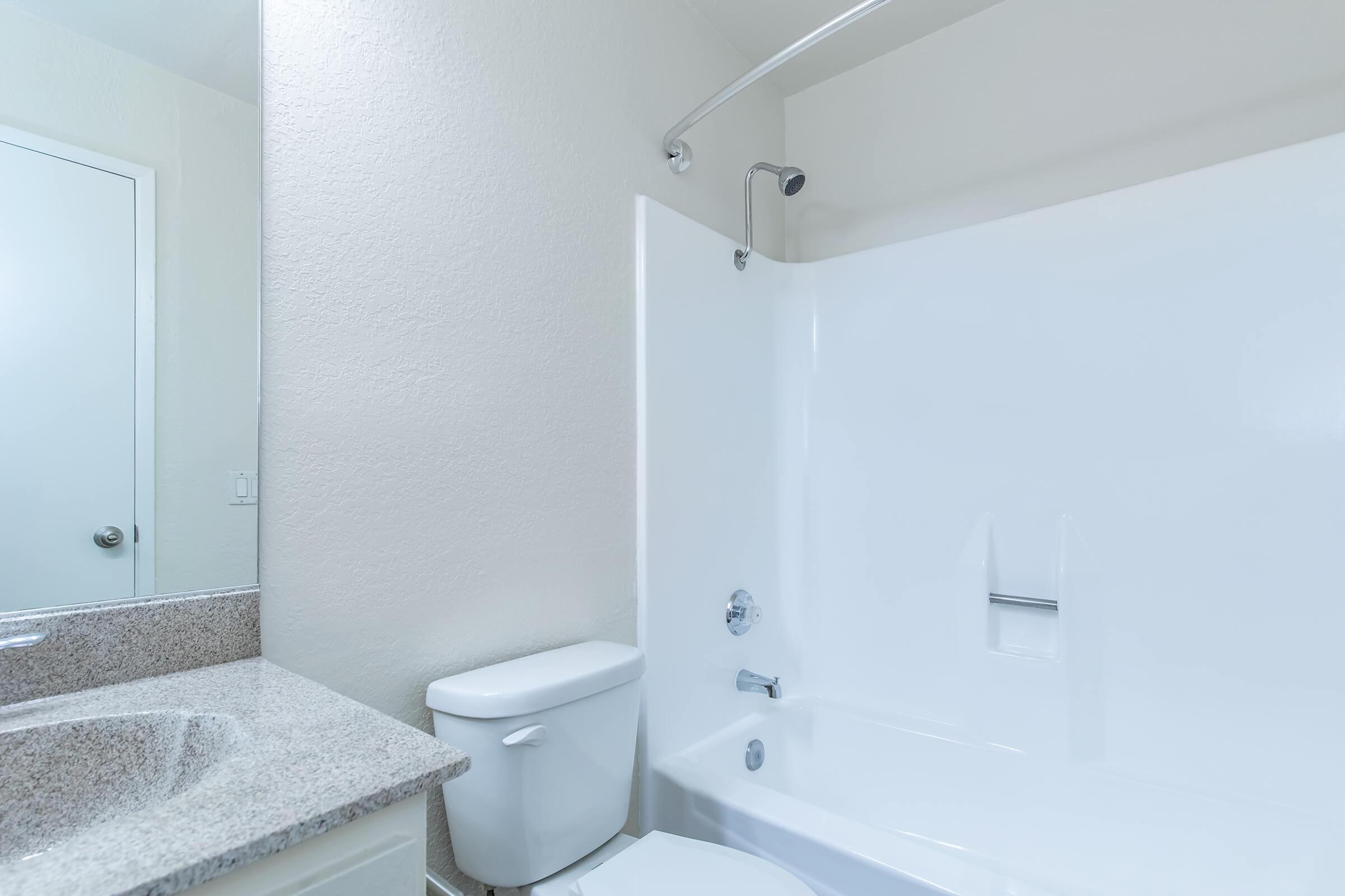 bathroom with white shower tiles and grey countertops