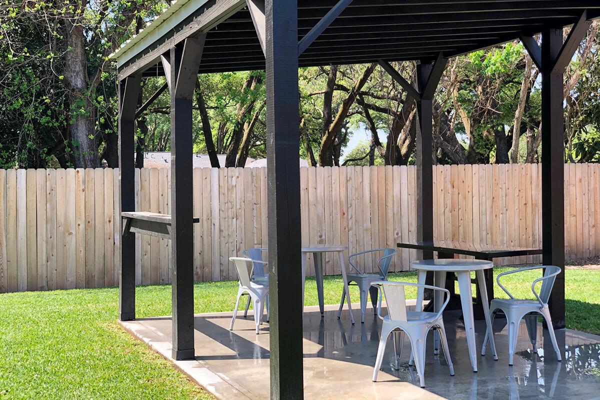 a group of people sitting at a table in front of a fence