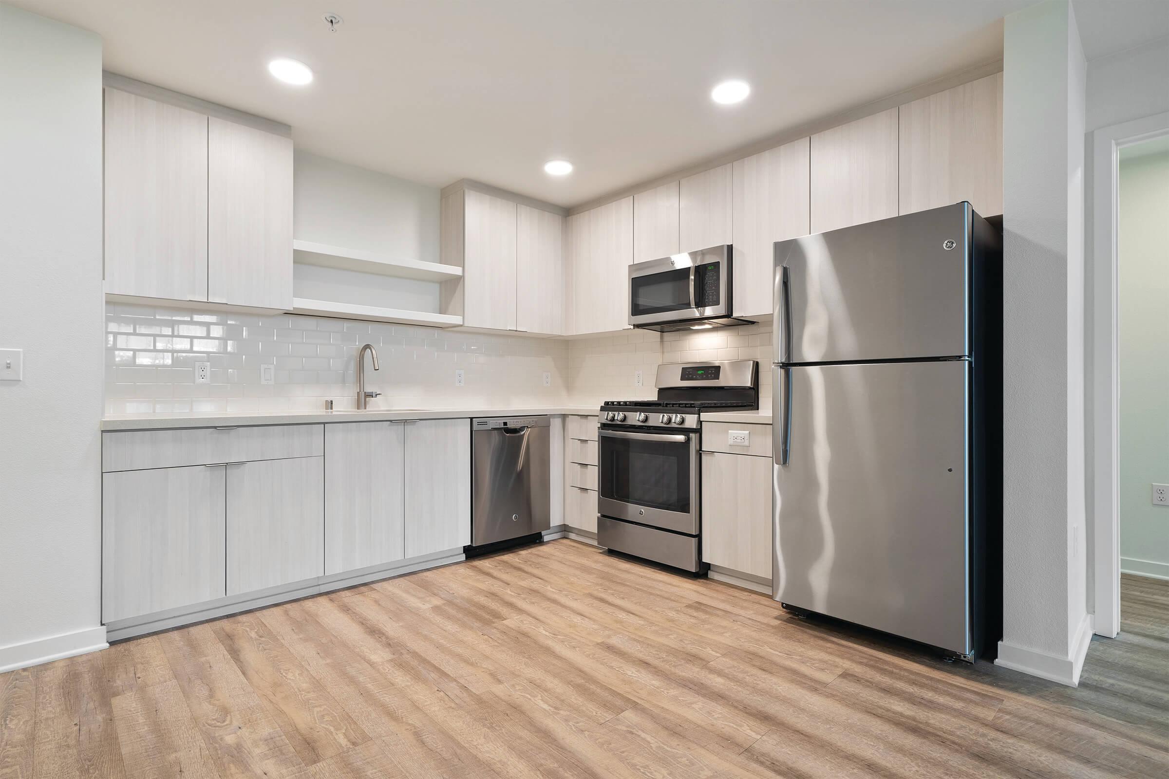 Kitchens include quartz countertops, tile backsplash, and stainless or slate finish appliances