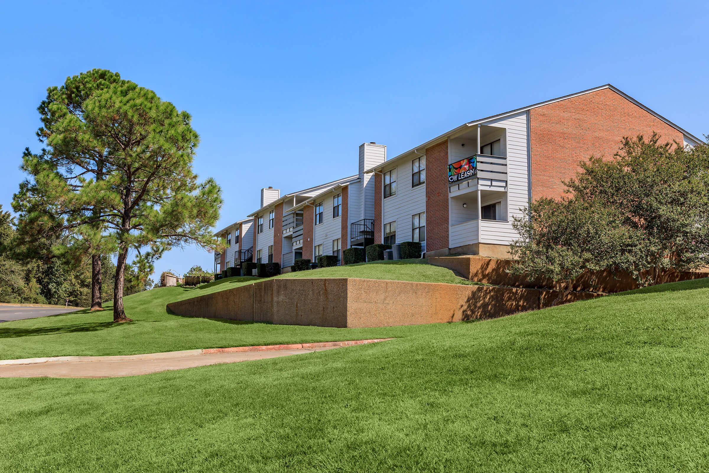 a large brick building with grass in front of a house