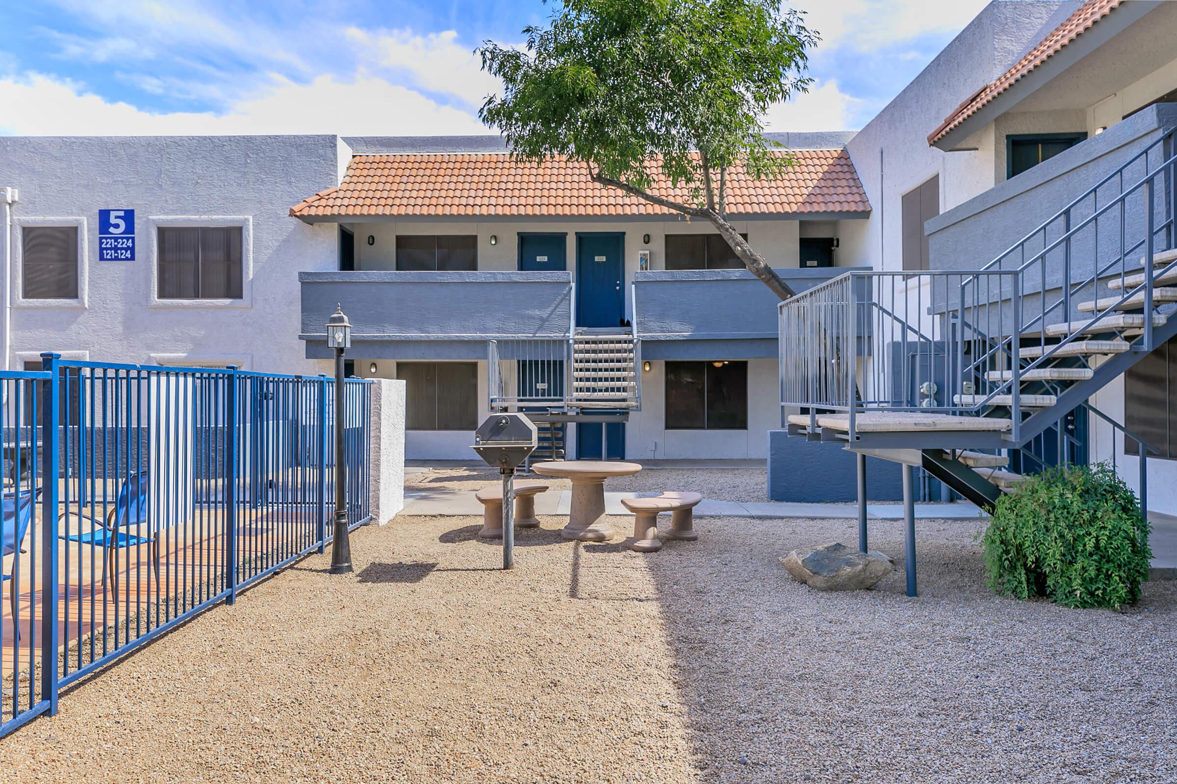 The BBQ area near the fenced pool and stairs leading to the apartments at Rise Trailside.