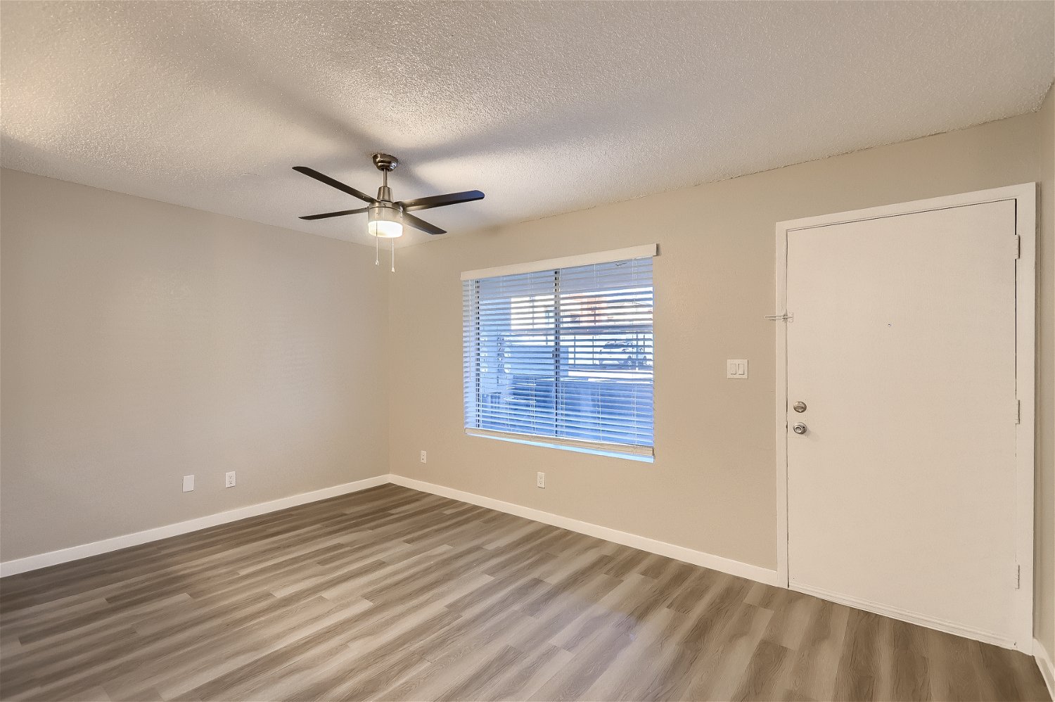 The door and living room with wood-style flooring and a large window at Rise Trailside.