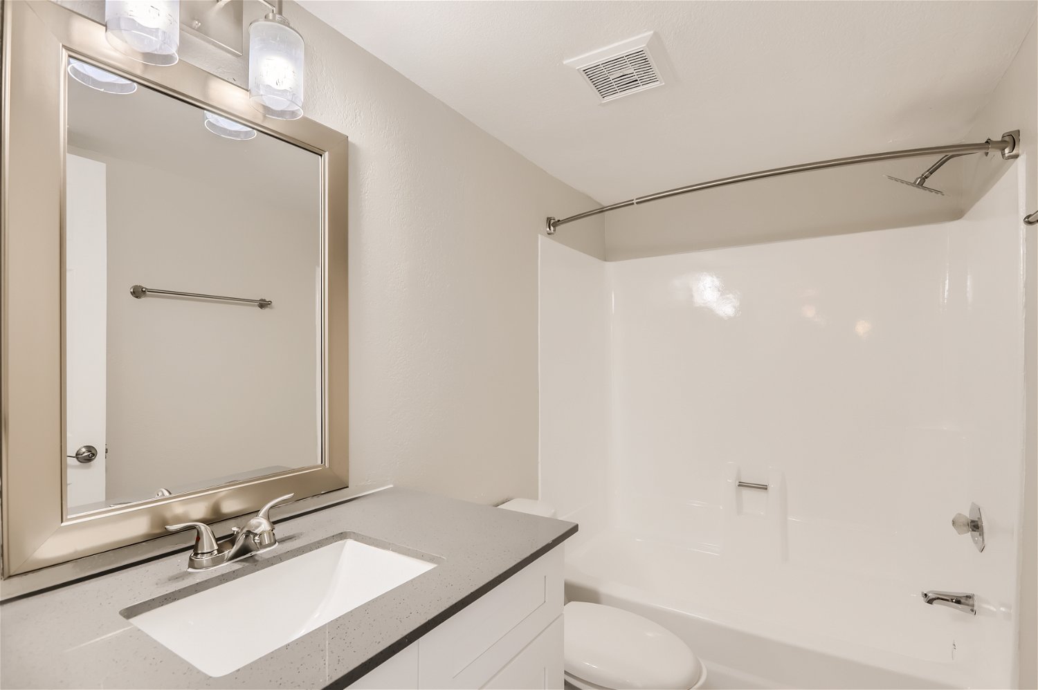 The remodeled bathroom with a tub, quartz vanity, and mirror at Rise Trailside.