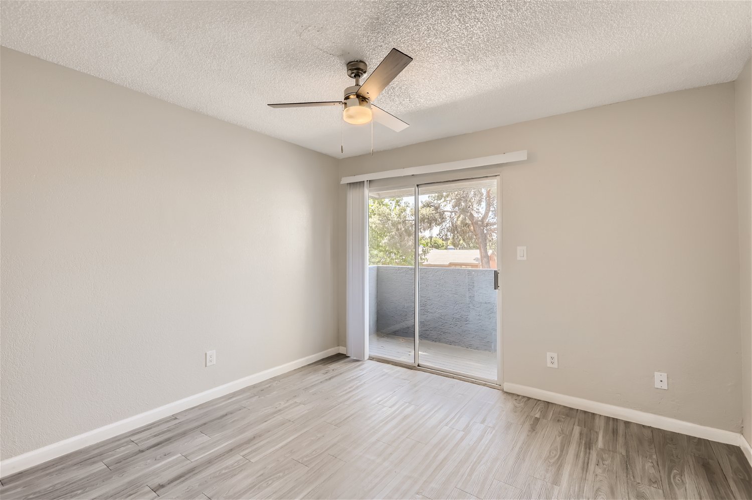 The living room with a sliding glass door leading to a balcony at Rise Trailside.