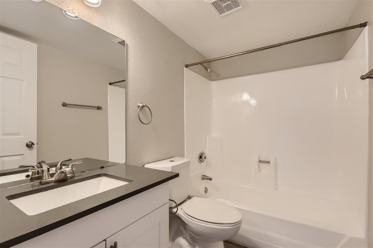 A bathroom with grey a quartz countertop and a tub at Rise Trailside. 