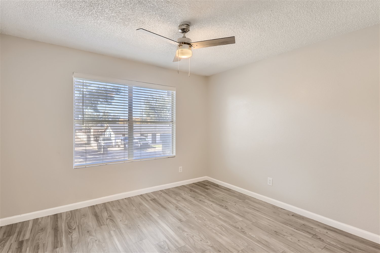 A bedroom with a ceiling fan, a window, and wood-style flooring at Rise Trailside.