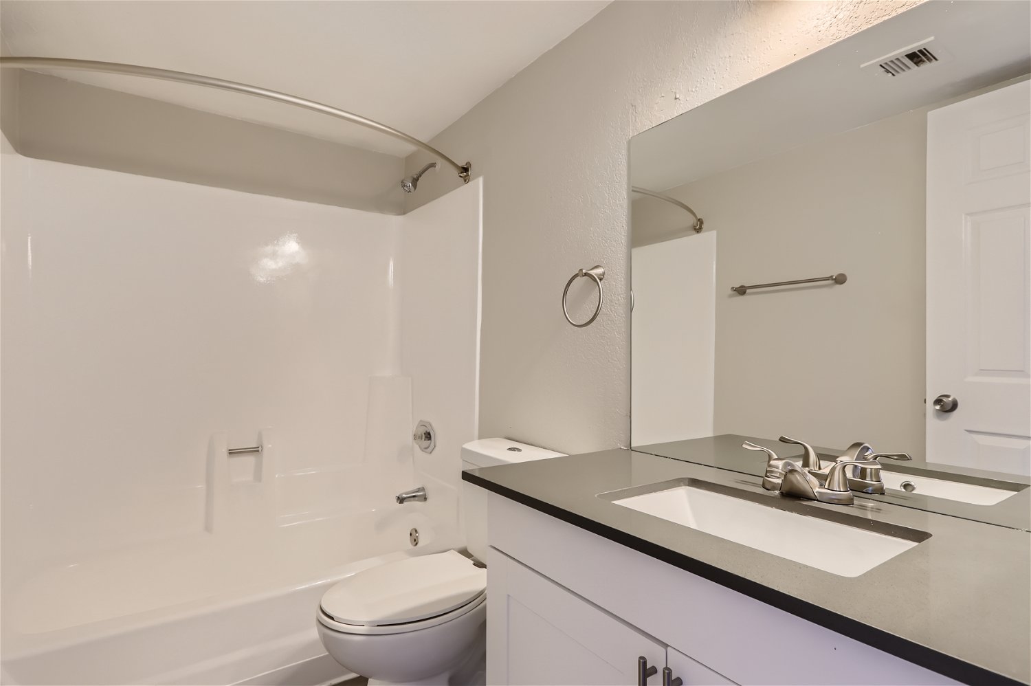 A remodeled bathroom with a tub, quartz vanity, and a mirror at Rise Trailside.