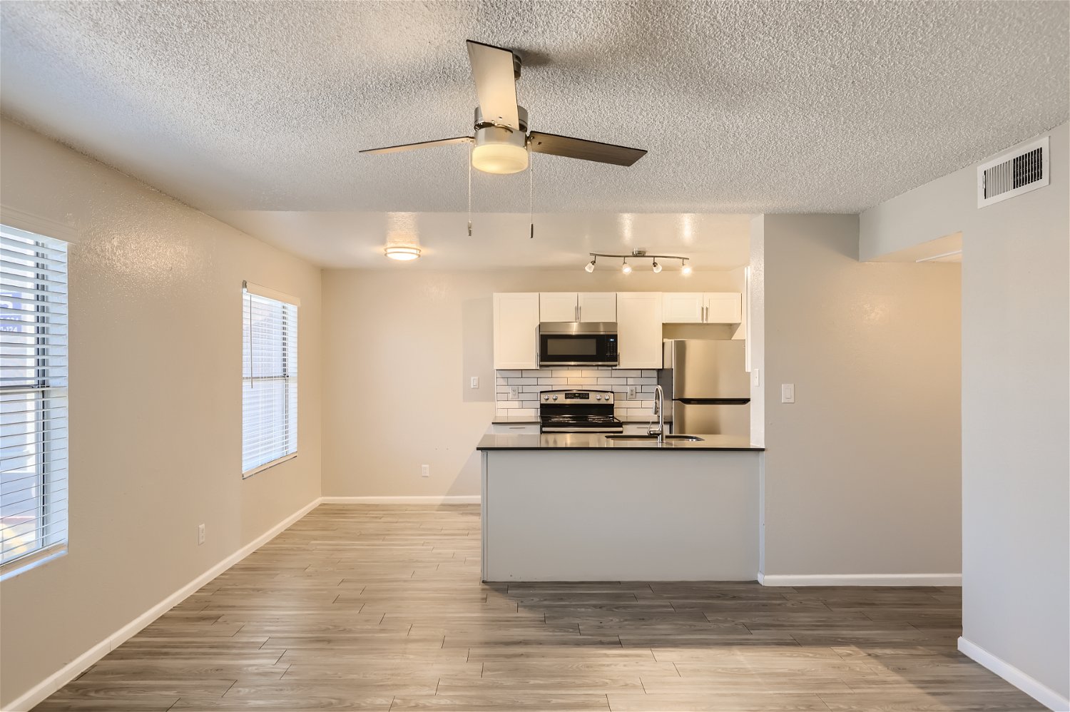 The living area with a kitchen and wood-style floors at Rise Trailside. 