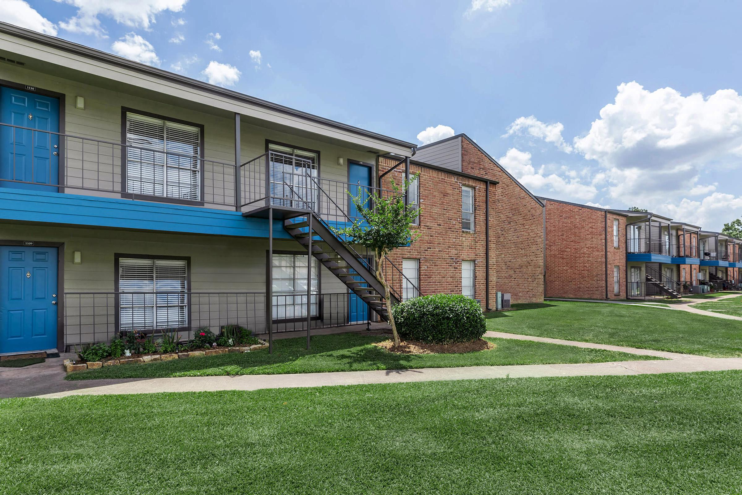 a house with a lawn in front of a brick building