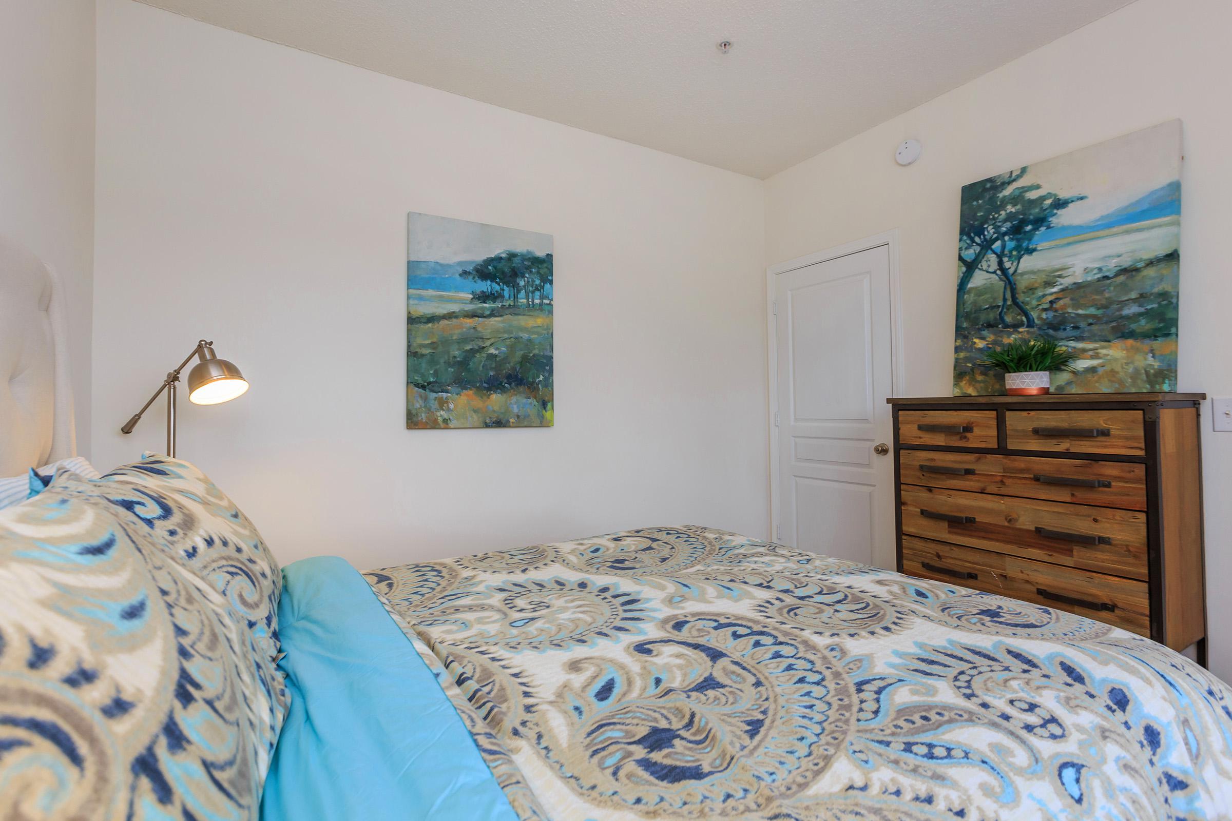 a bedroom with a bed and a painting on the corner of a room