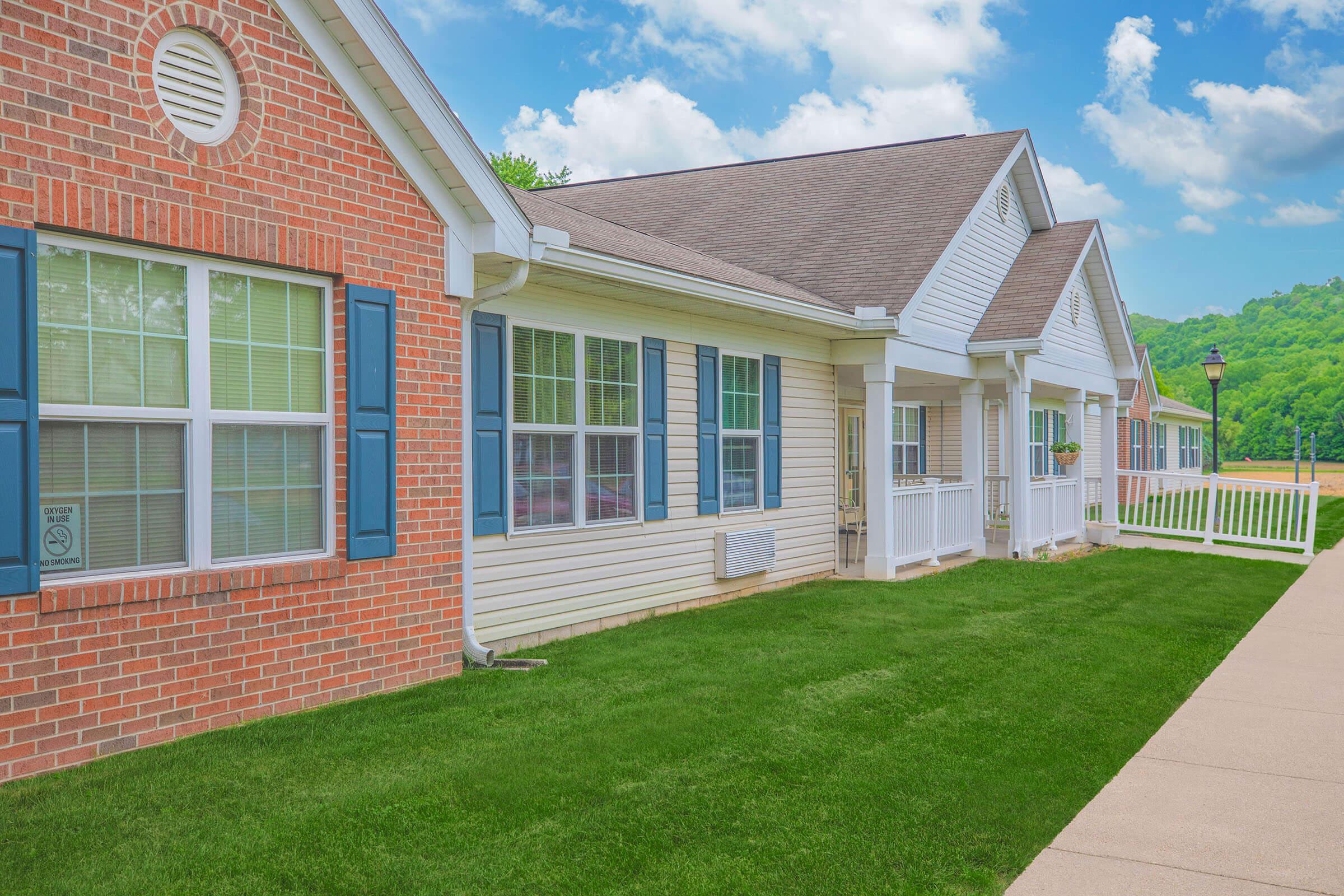 a large brick building with grass in front of a house