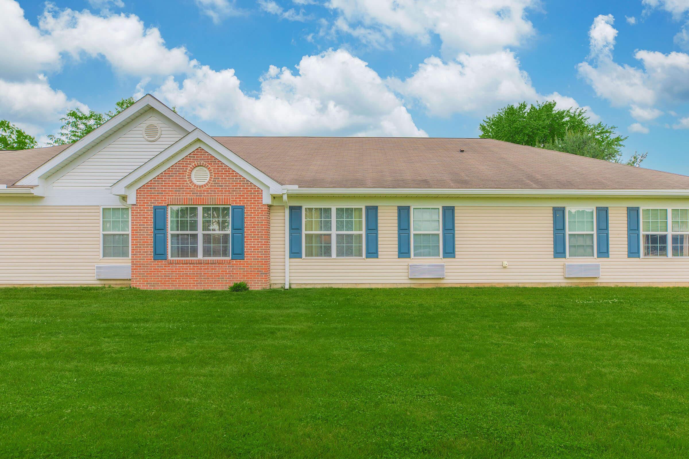 a large brick building with grass in front of a house