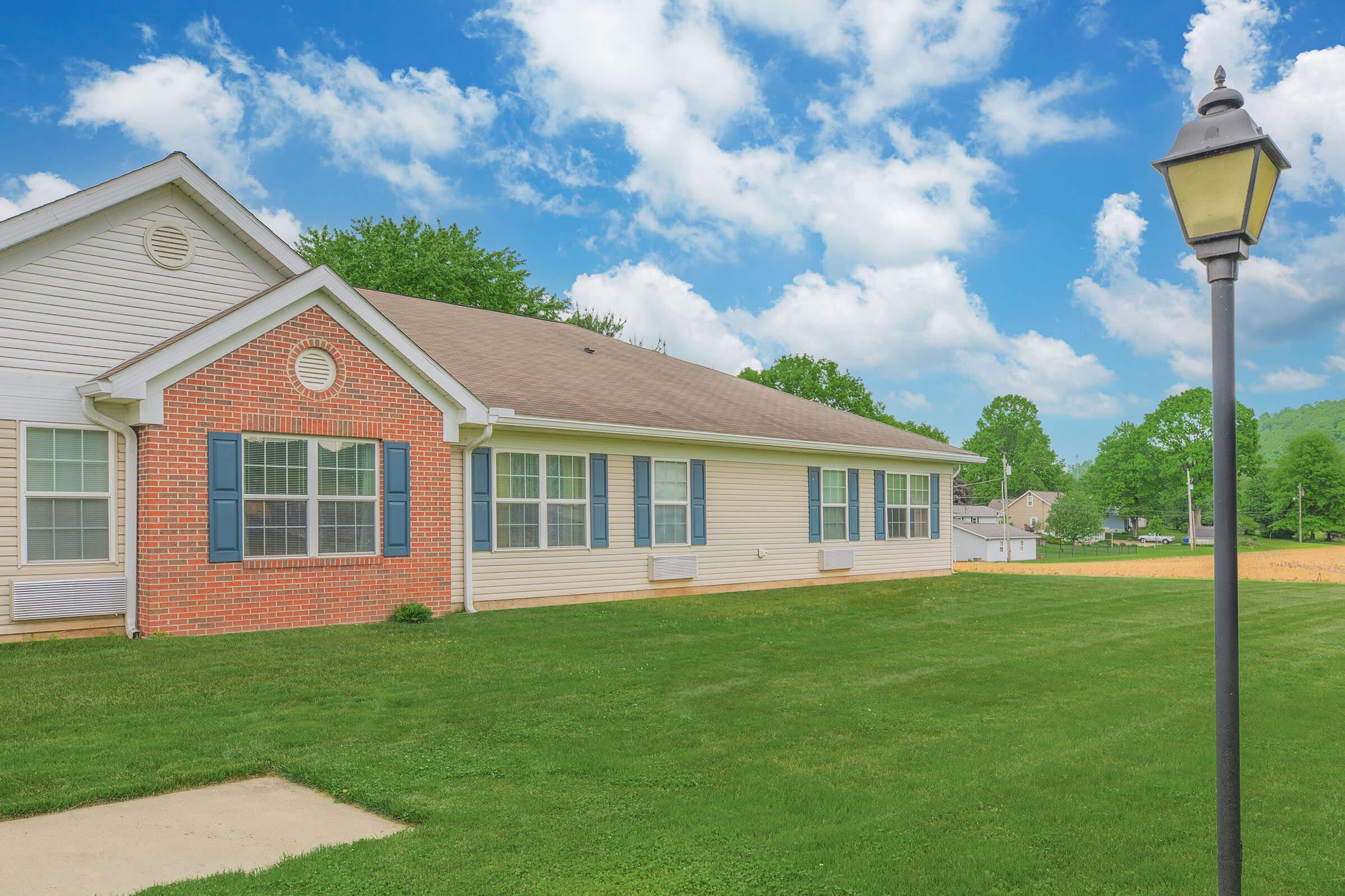 a large brick building with grass in front of a house