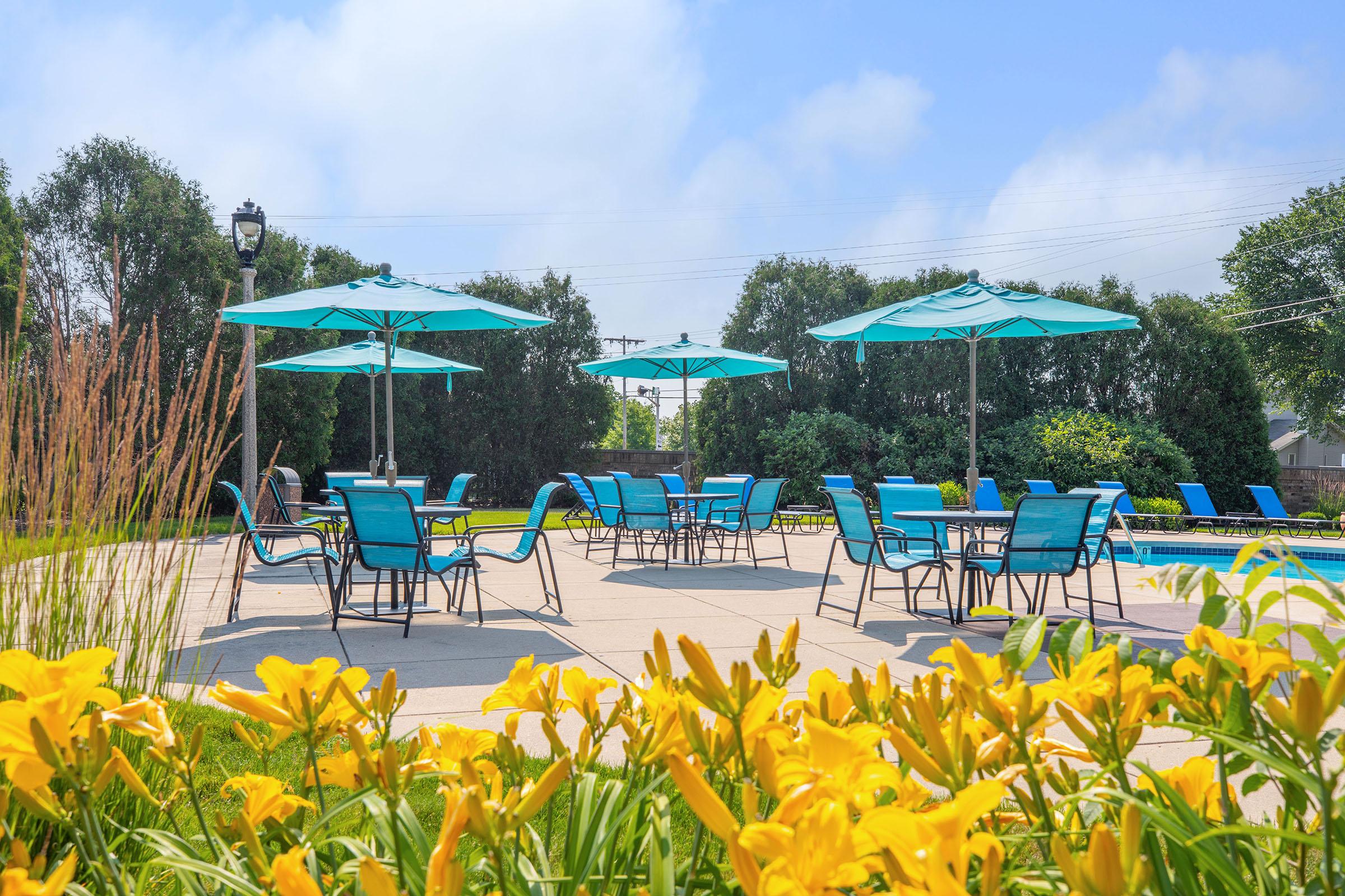 a group of people sitting at a table with a blue umbrella