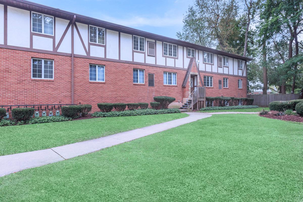 a large brick building with grass in front of a house