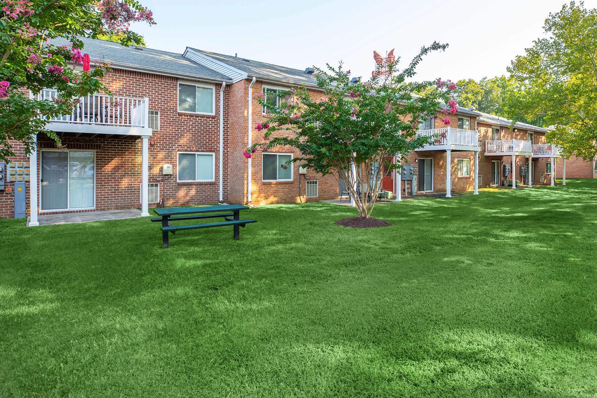 a house with a lawn in front of a brick building