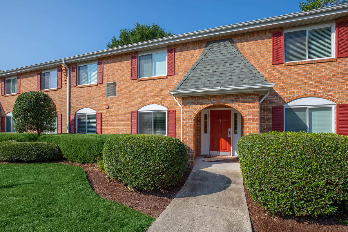 a large brick building with green grass in front of a house