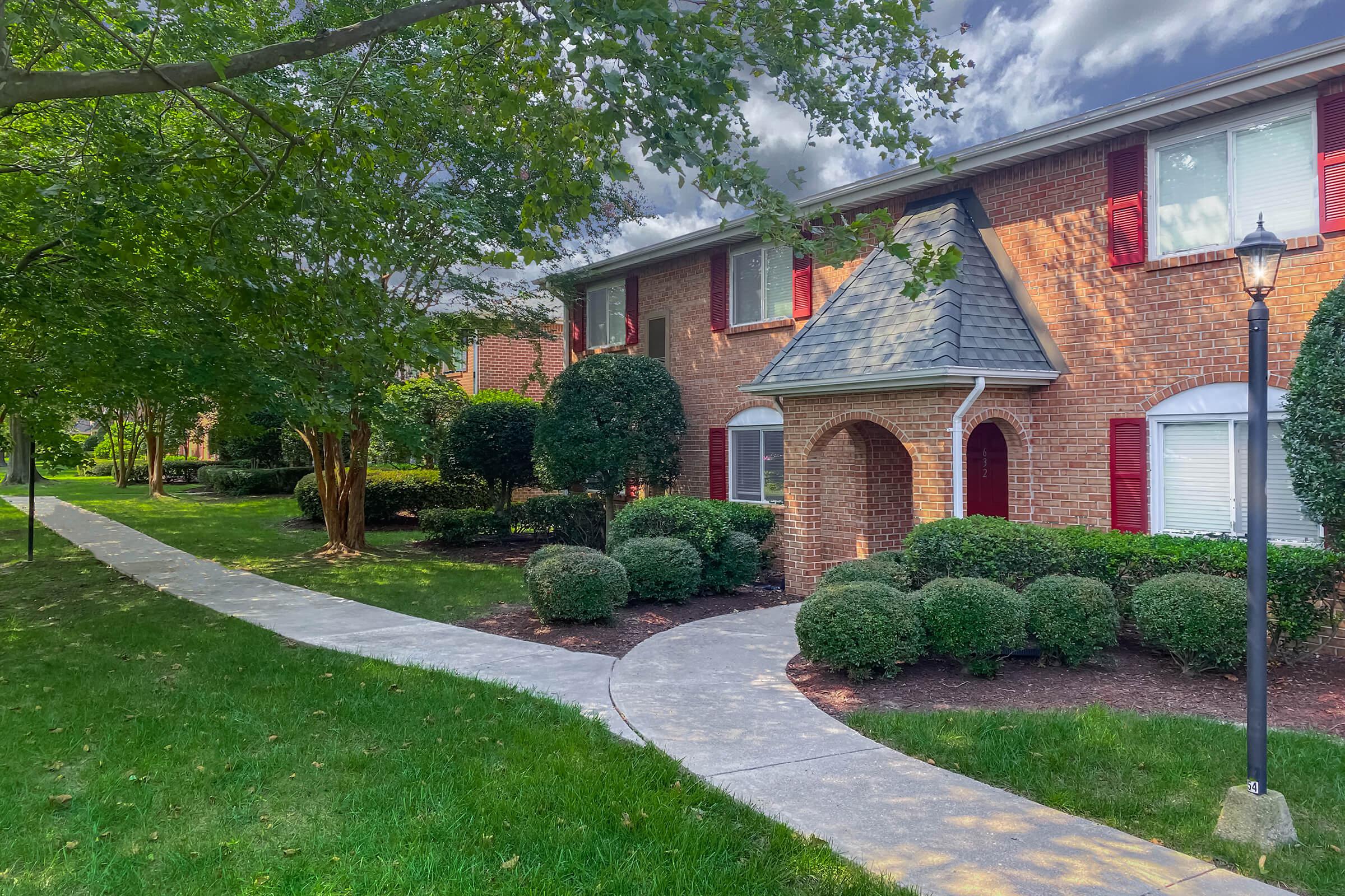 a large brick building with grass in front of a house