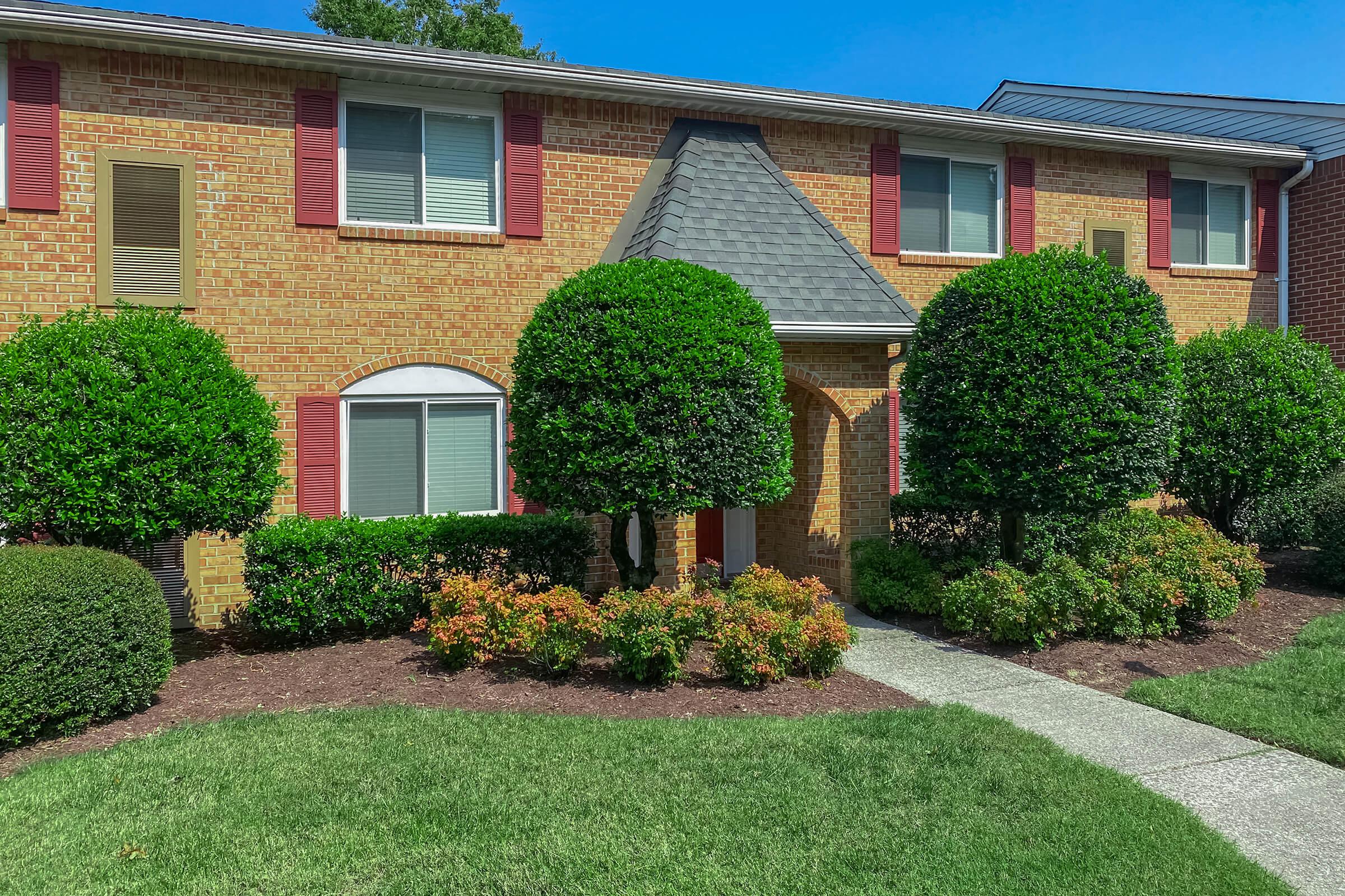 a large brick building with green grass in front of a house