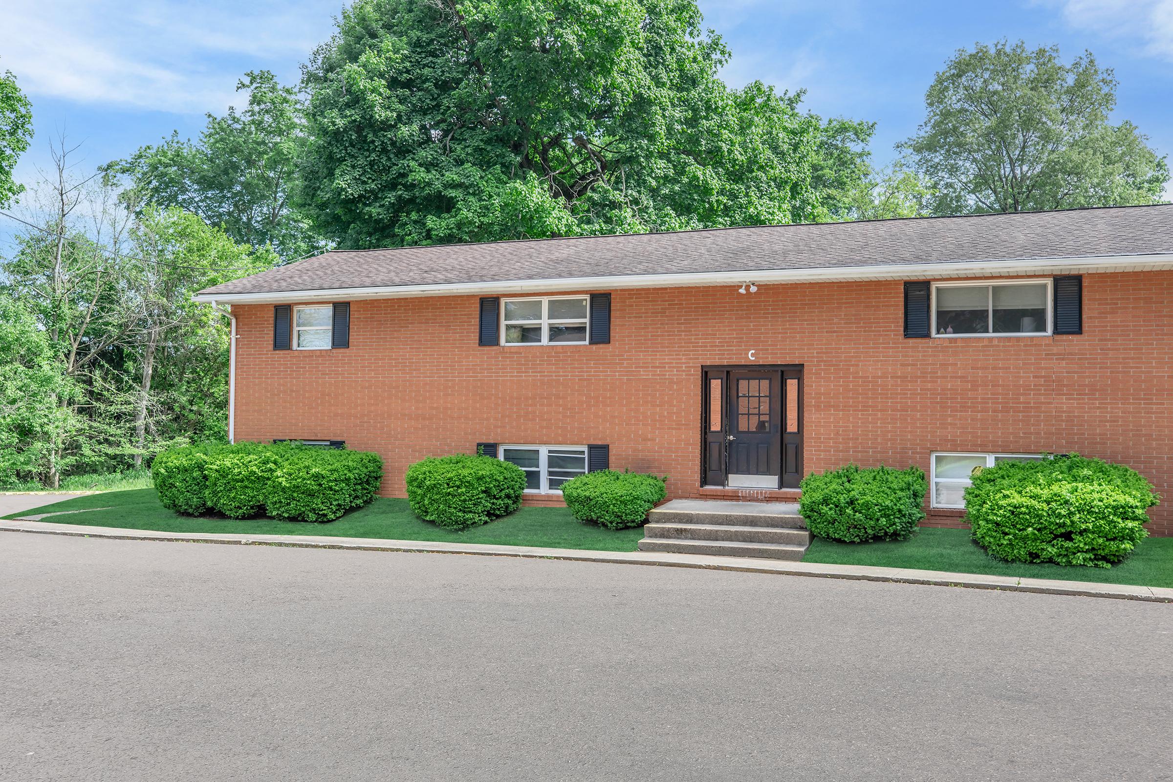 a house with bushes in front of a brick building