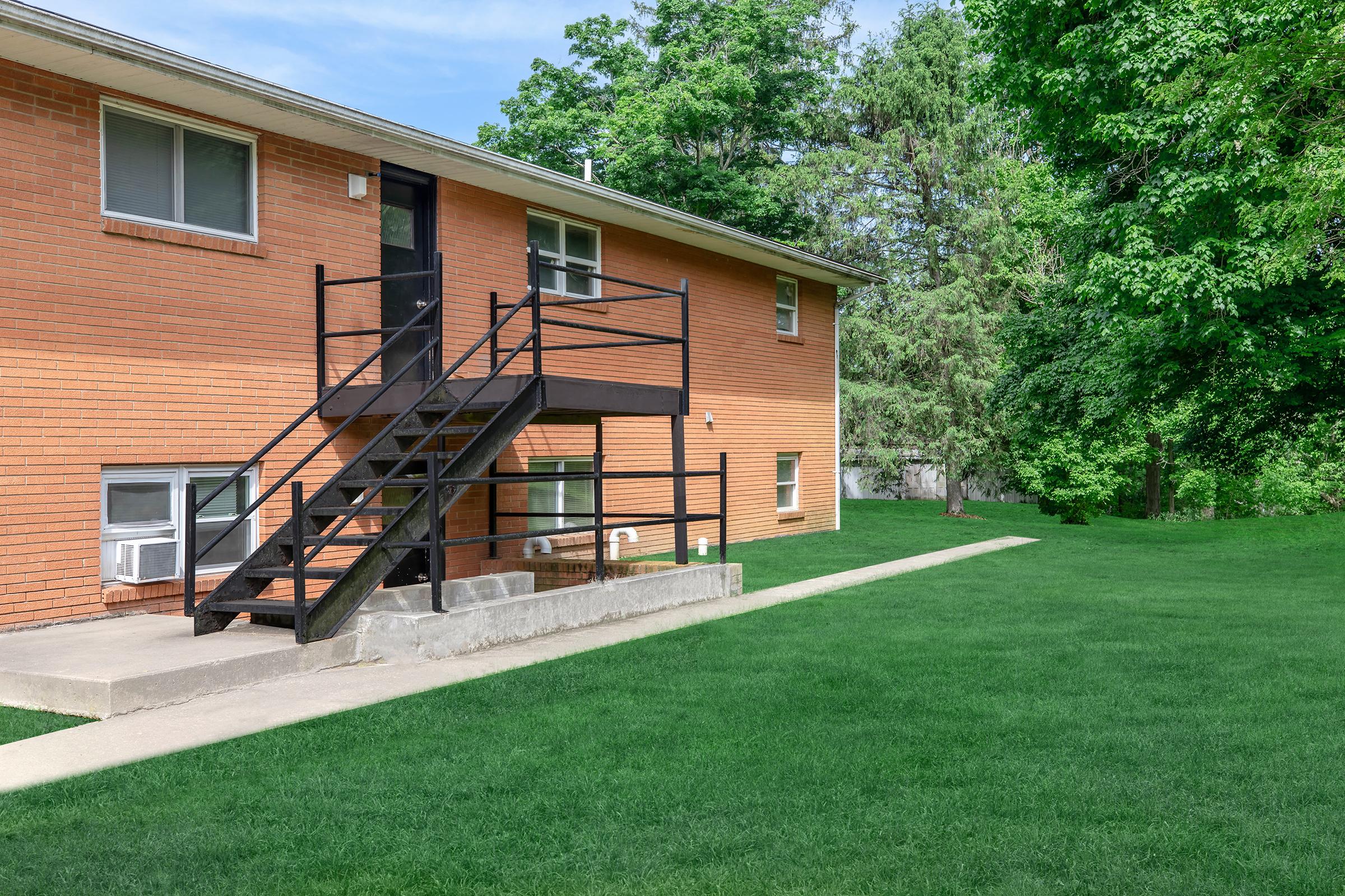 a house with a lawn in front of a brick building