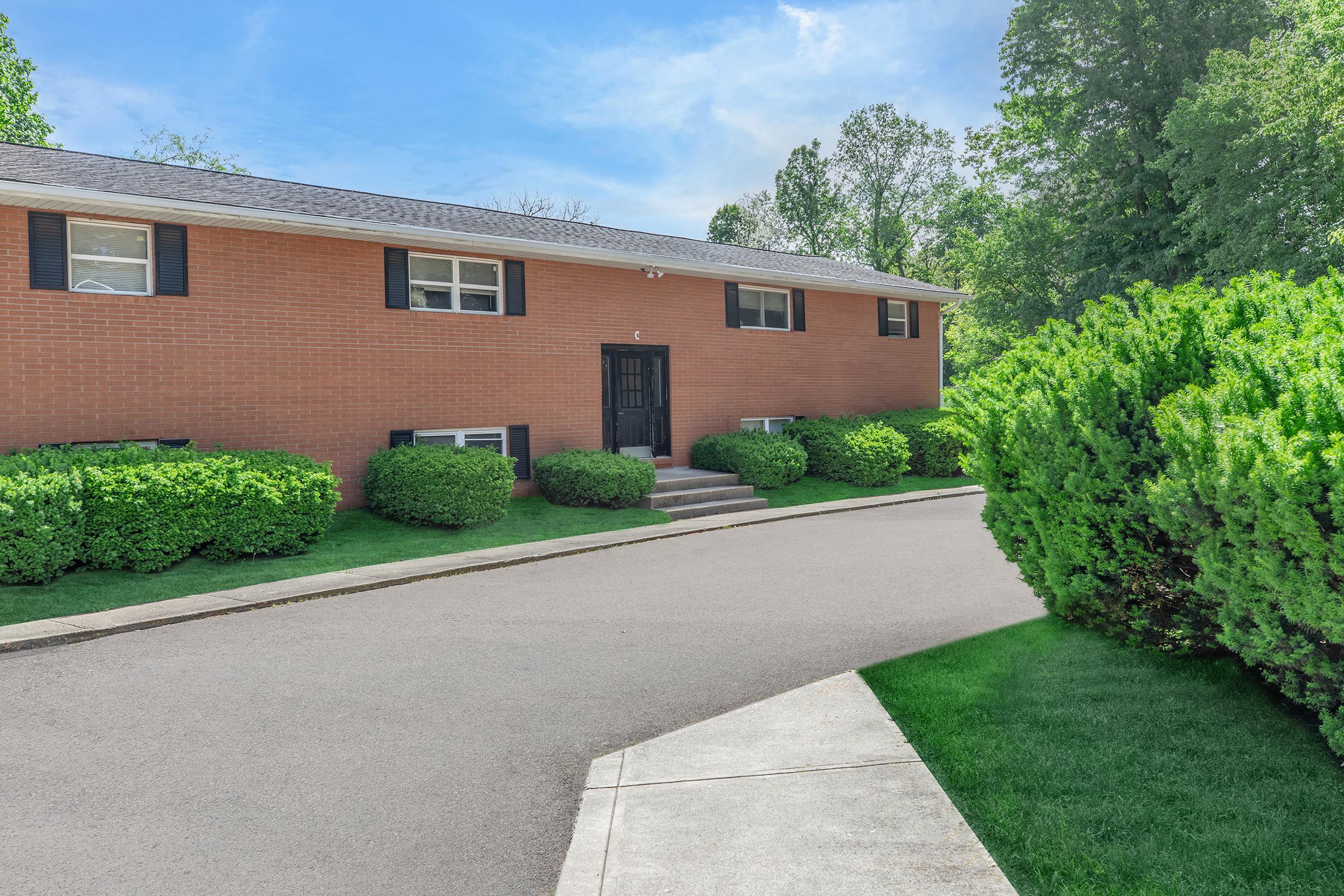 a large brick building with grass in front of a house