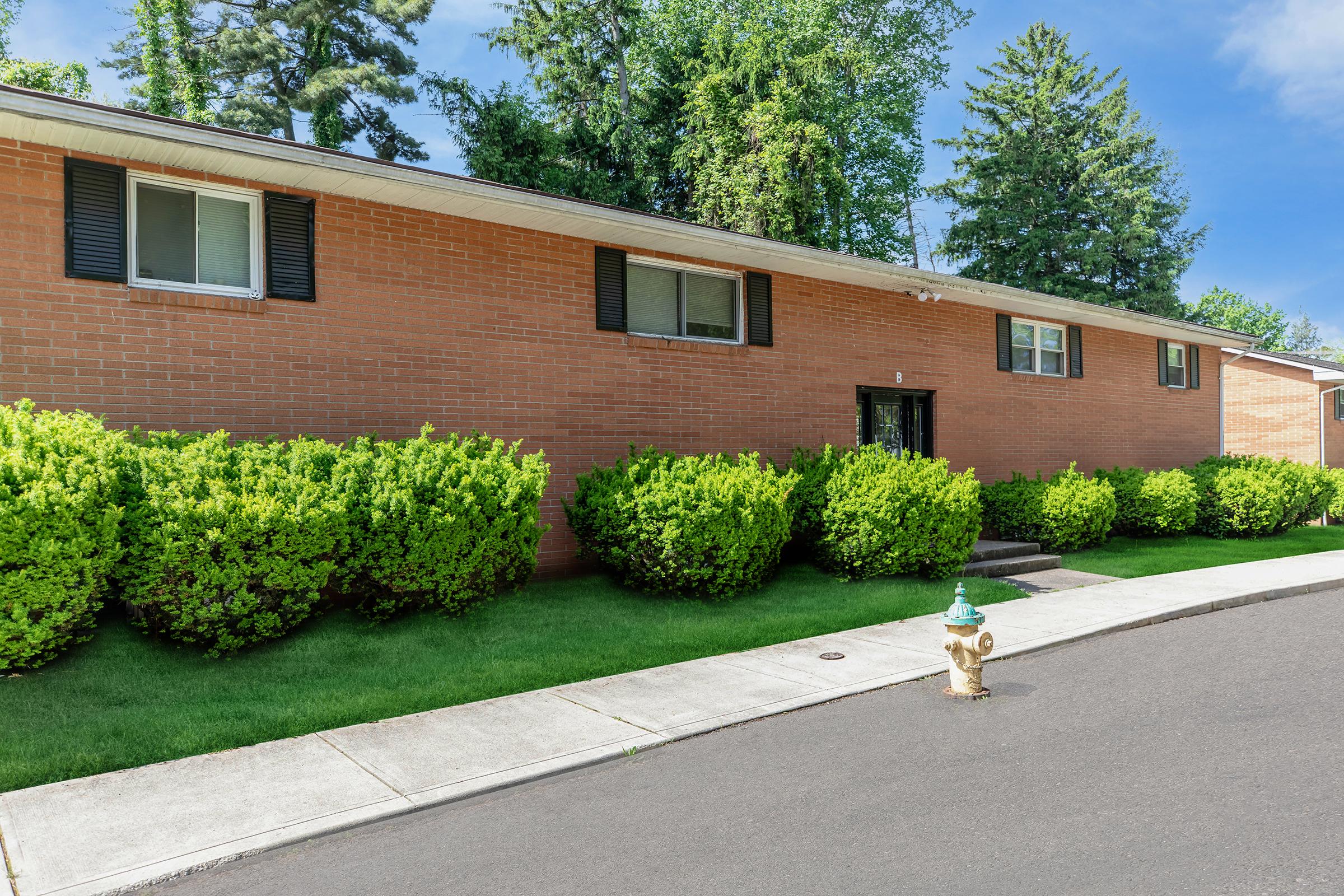 a brick building with green grass in front of a house