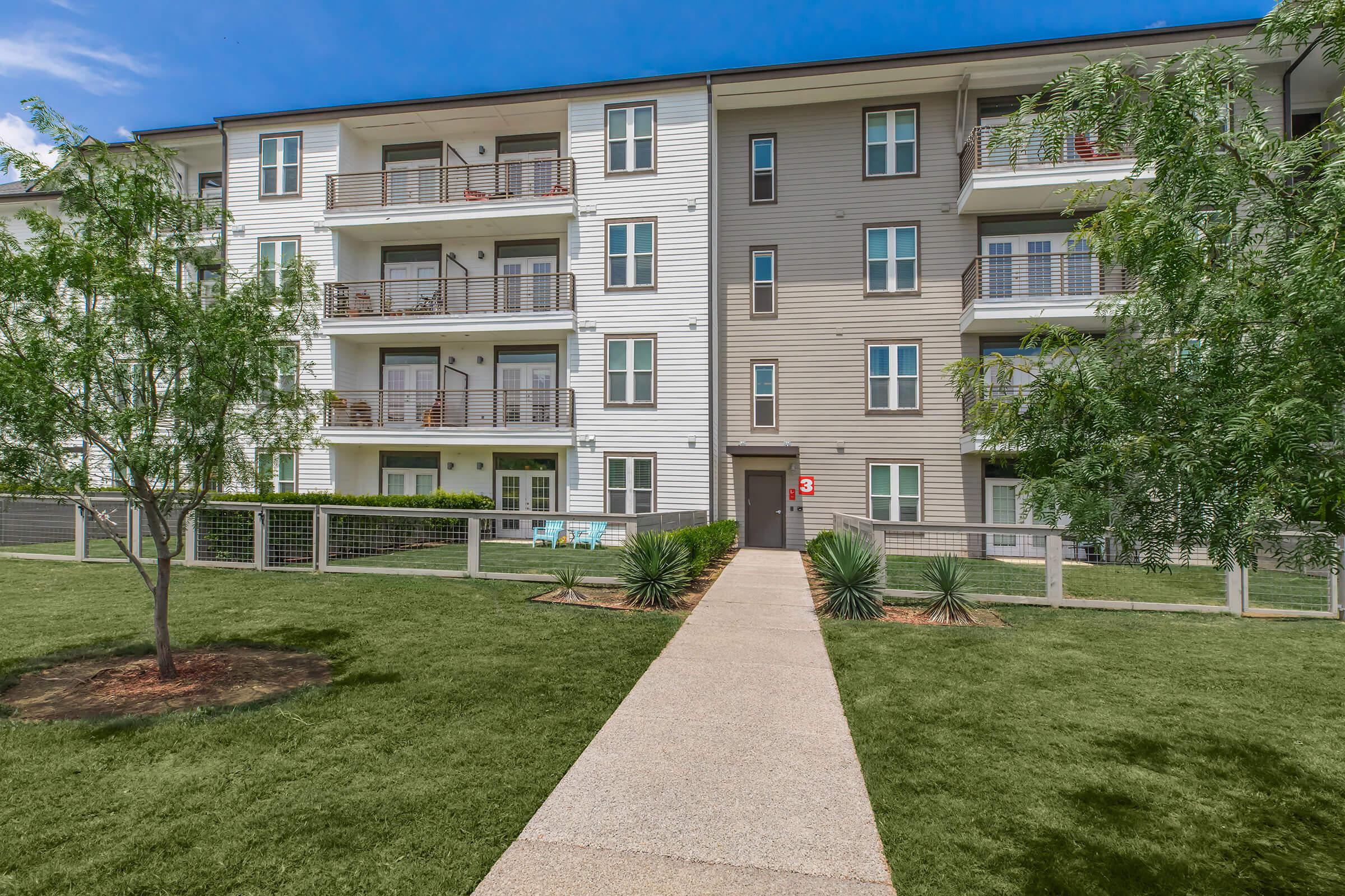 Farmhouse Apartments community building with green trees