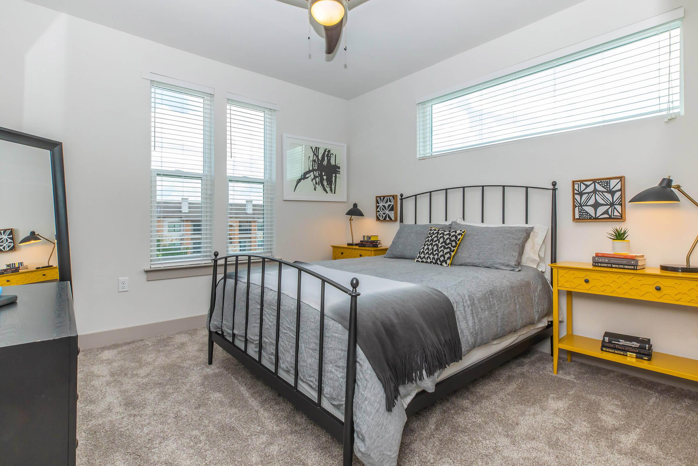 a bedroom with a grey comforter