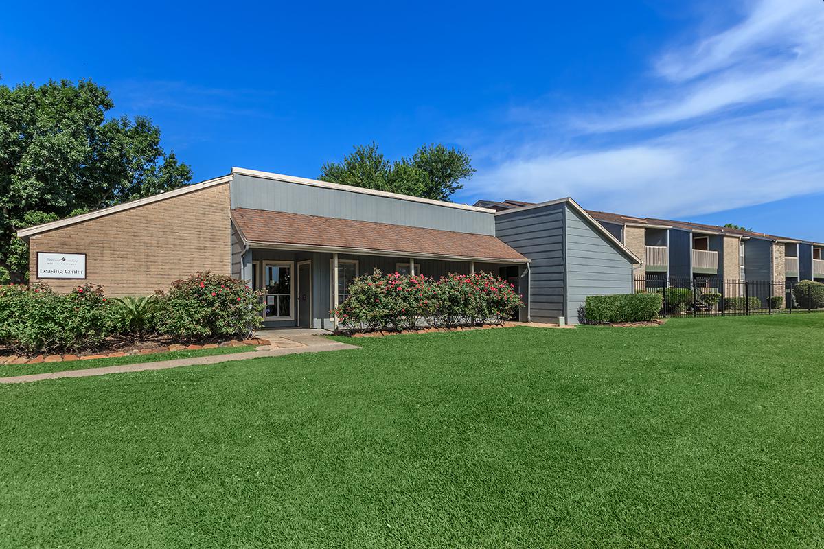 a large brick building with green grass in front of a house