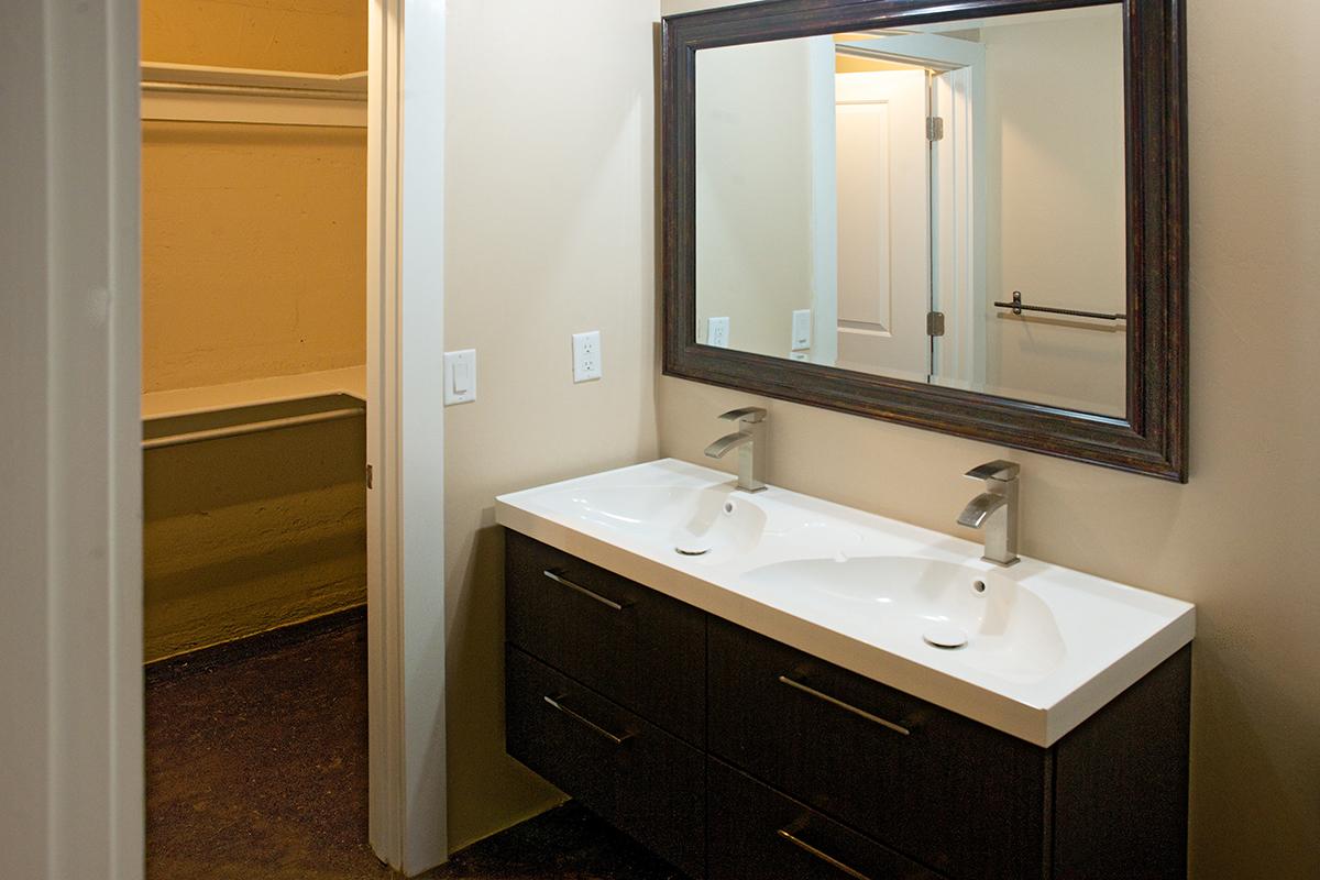 a white sink sitting under a mirror