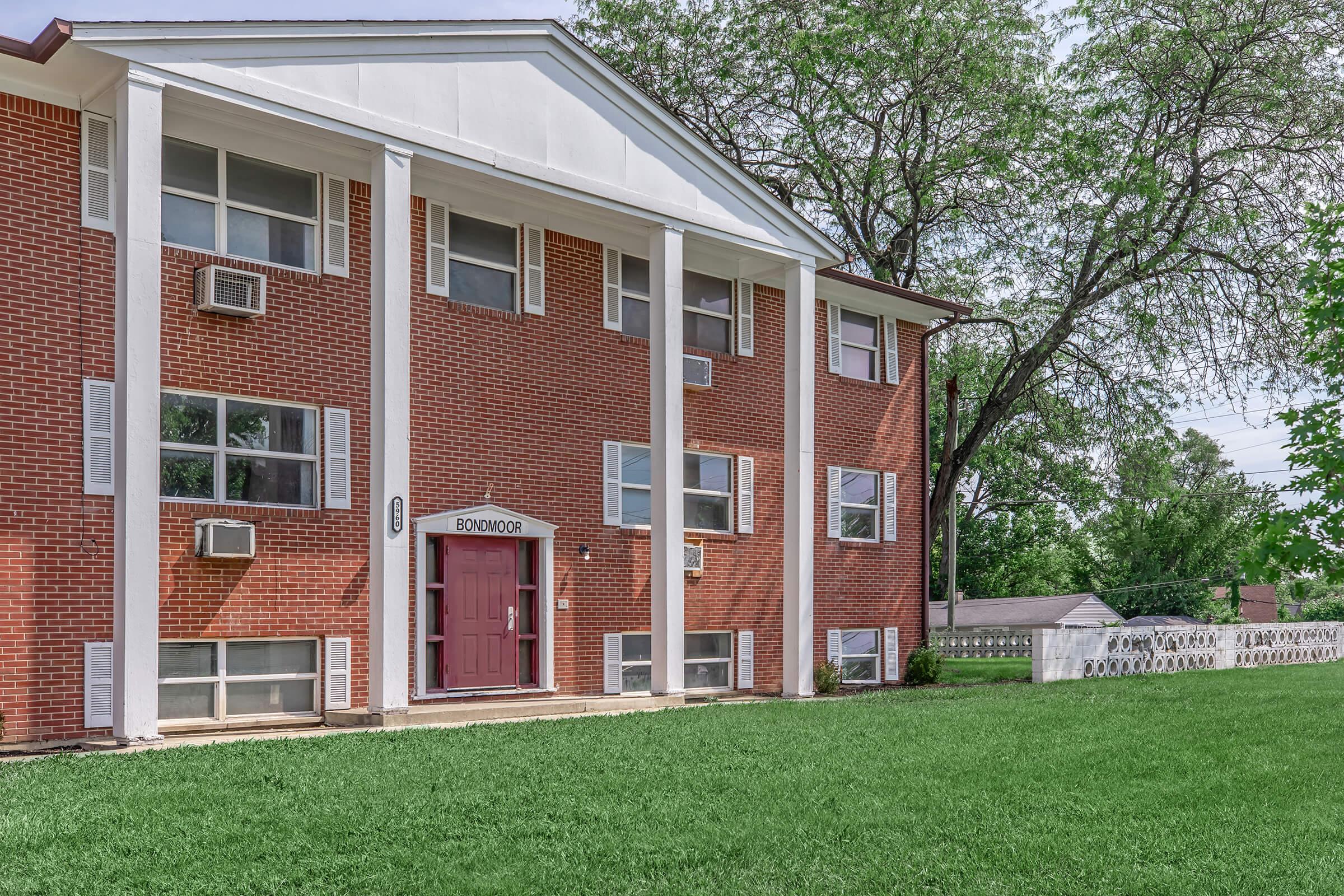 a house with a lawn in front of a brick building